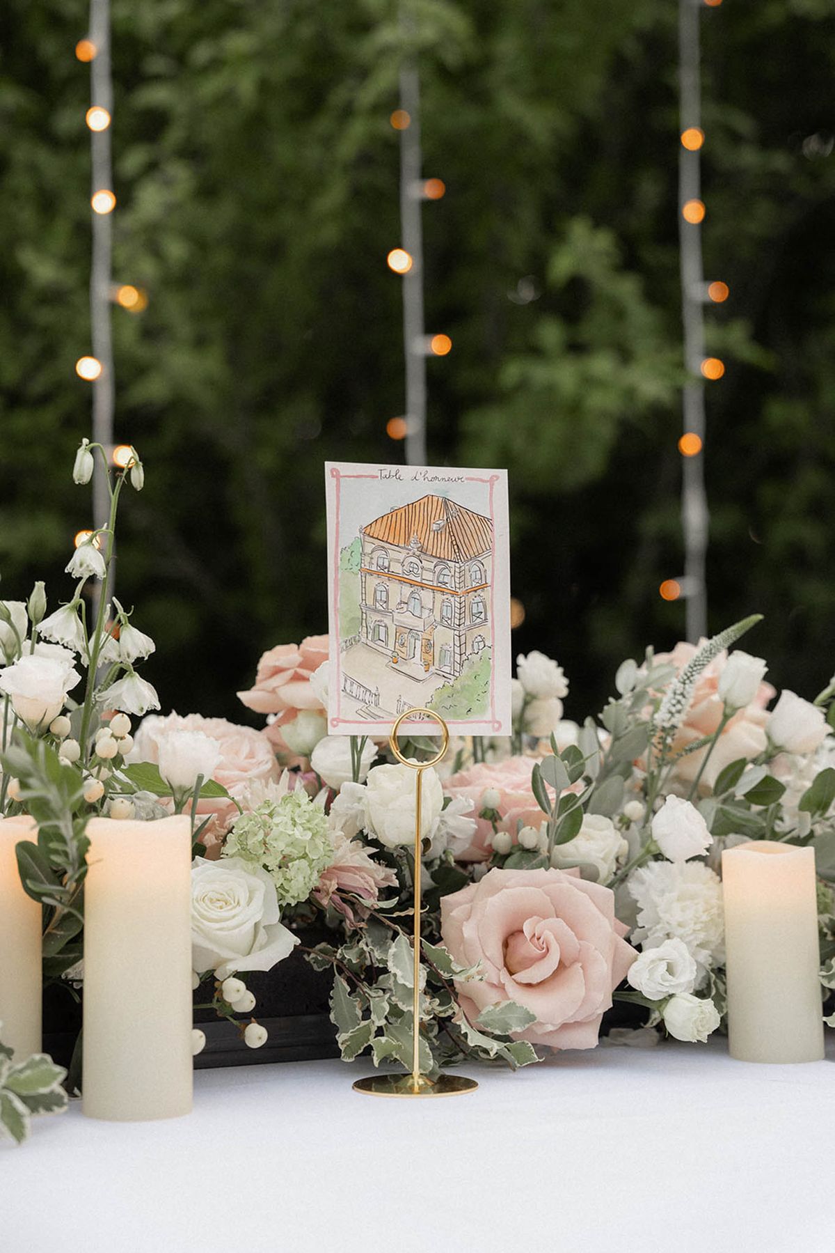 Reception centerpiece of blush roses, ivory hydrangeas and pampas grass in a black vessel with custom watercolor table number card.