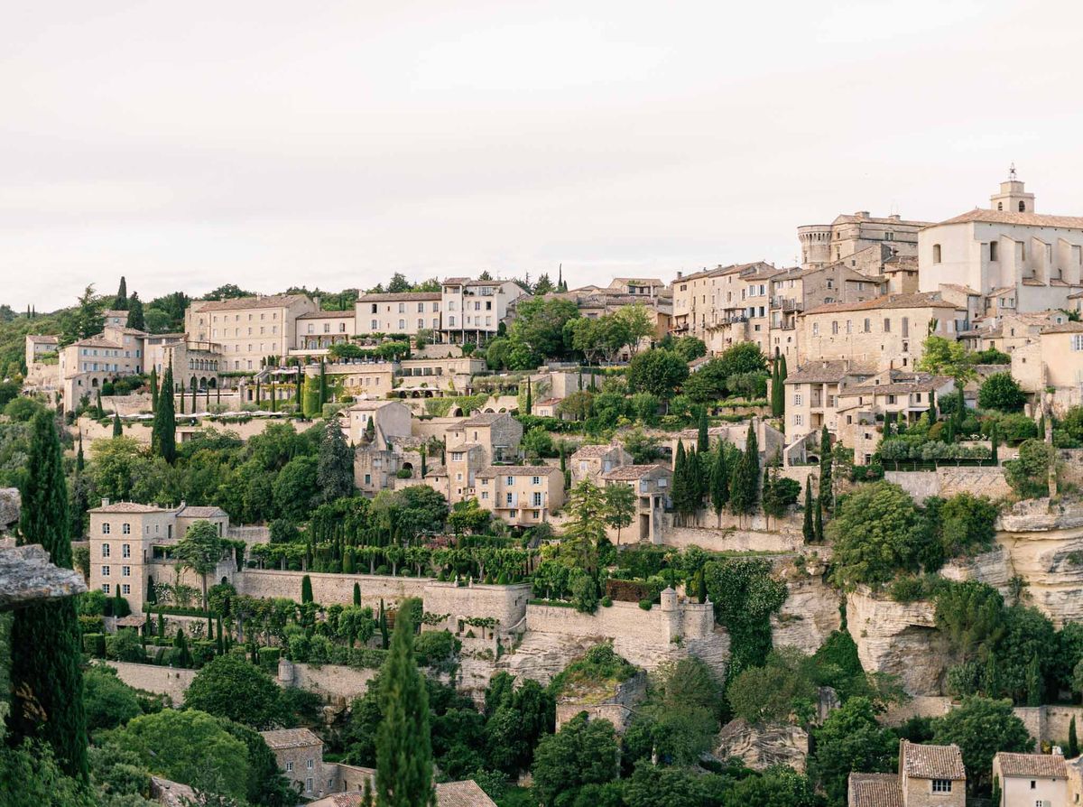 Panoramic view of a Provencal hilltop village with stone buildings, terracotta roofs, and cypress trees