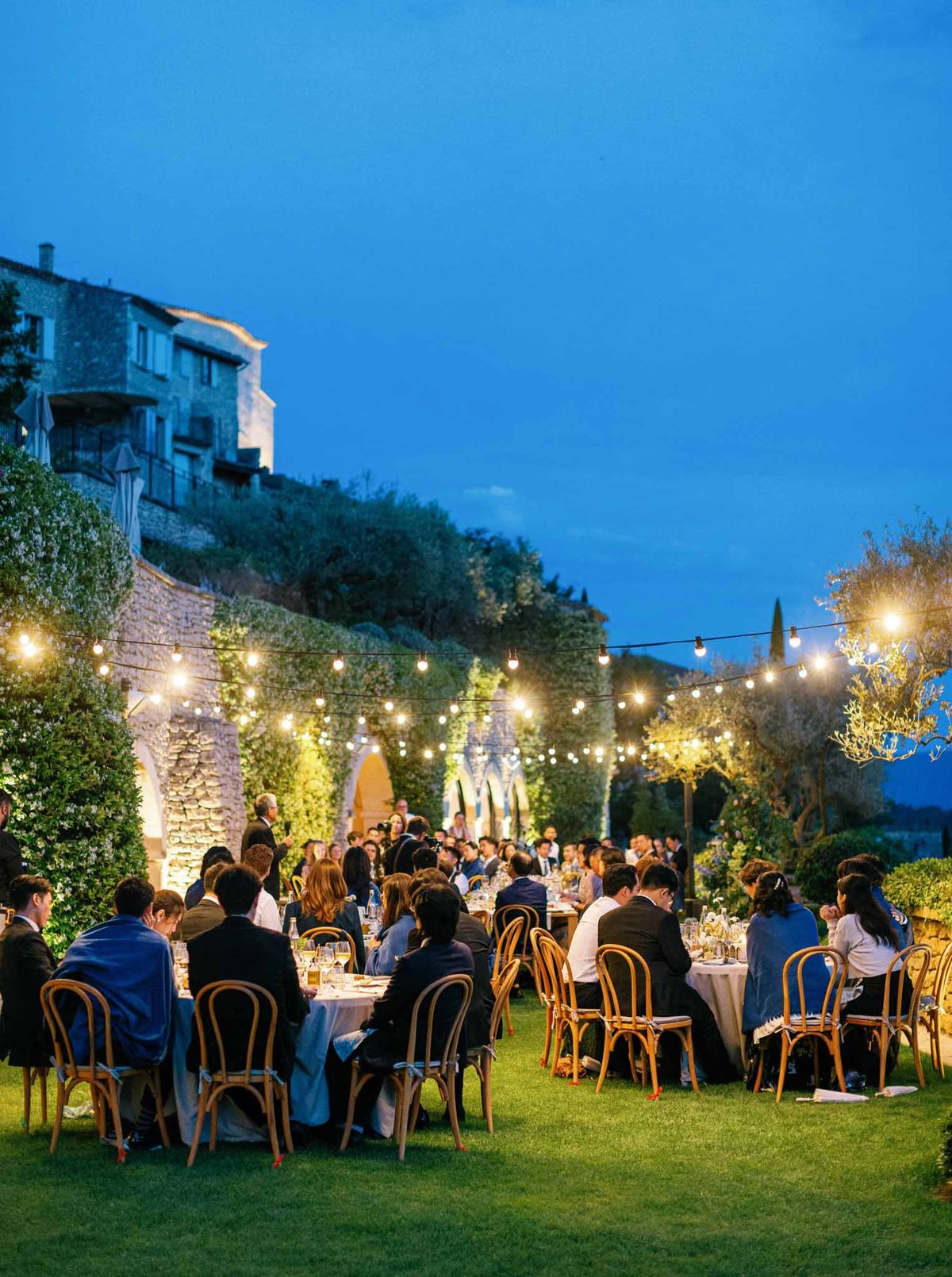 Evening outdoor reception with string lights on hillside garden terrace at Provencal venue