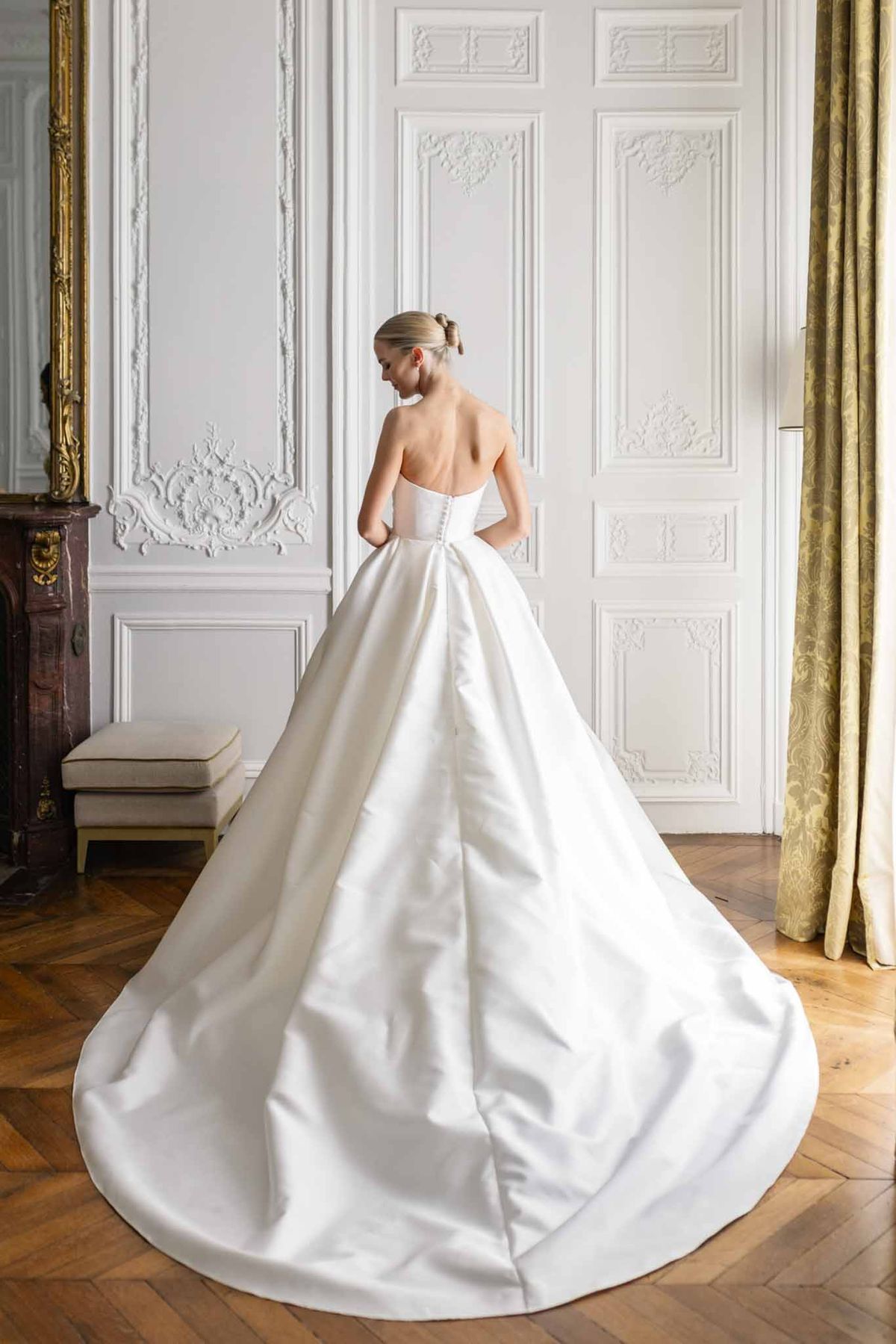 Bride seen from behind wearing ivory strapless ball gown with cathedral train in neoclassical gilded interior