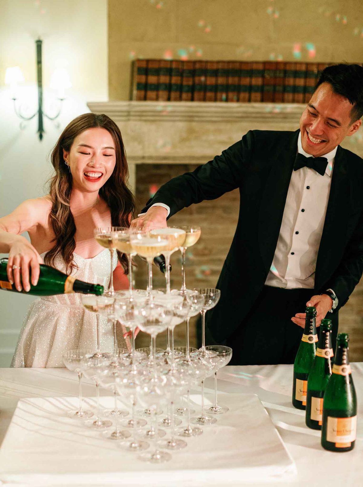Couple pouring champagne tower at indoor reception at Airelles Gordes La Bastide