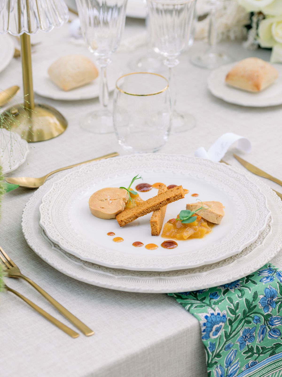 Plated foie gras with microgreens on white gold-rimmed plate at formal wedding reception with gold flatware