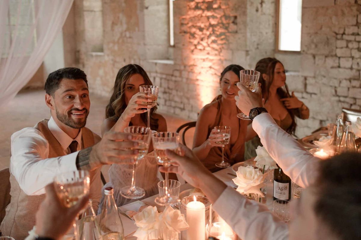 Guests raising glasses for reception toast in industrial brick venue