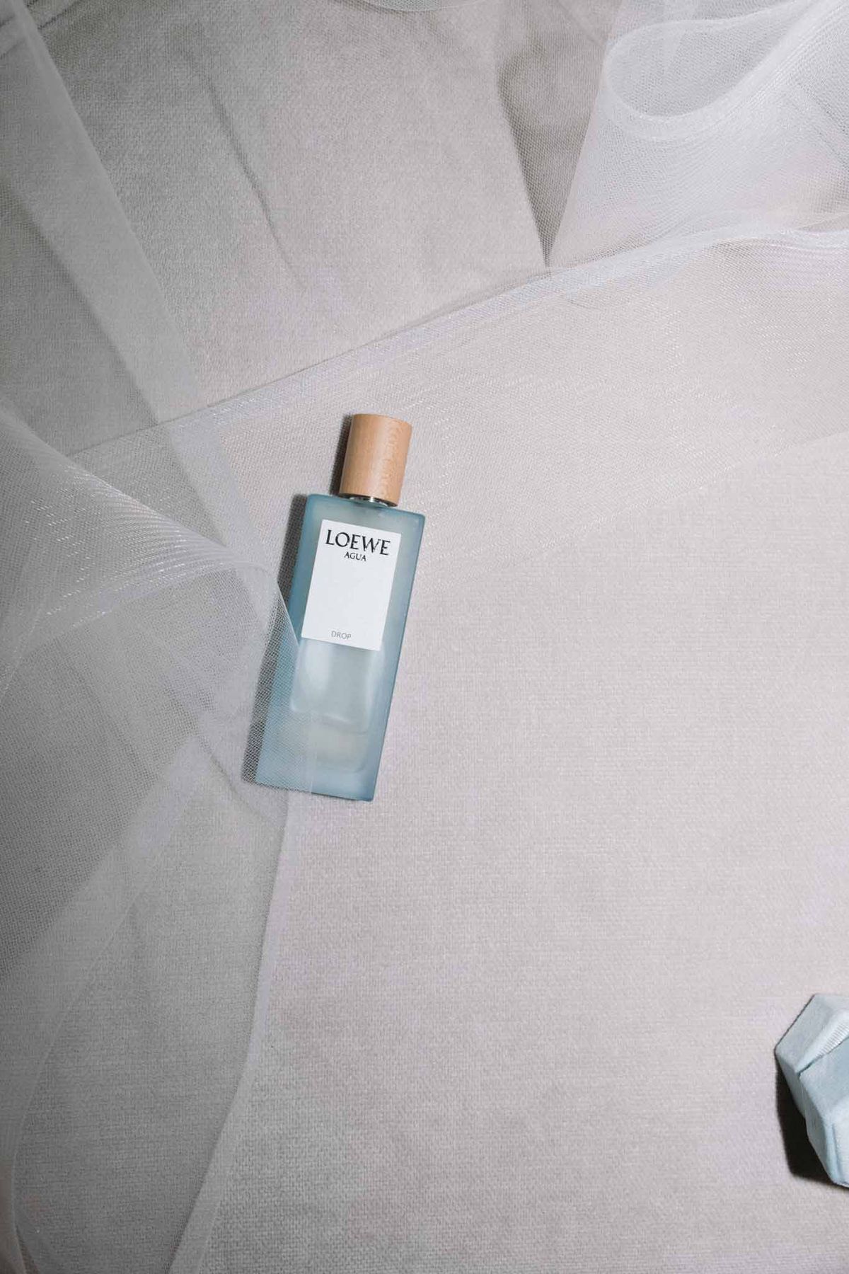 Loewe Agua fragrance bottle with gold cap on ivory tulle fabric, getting-ready detail shot