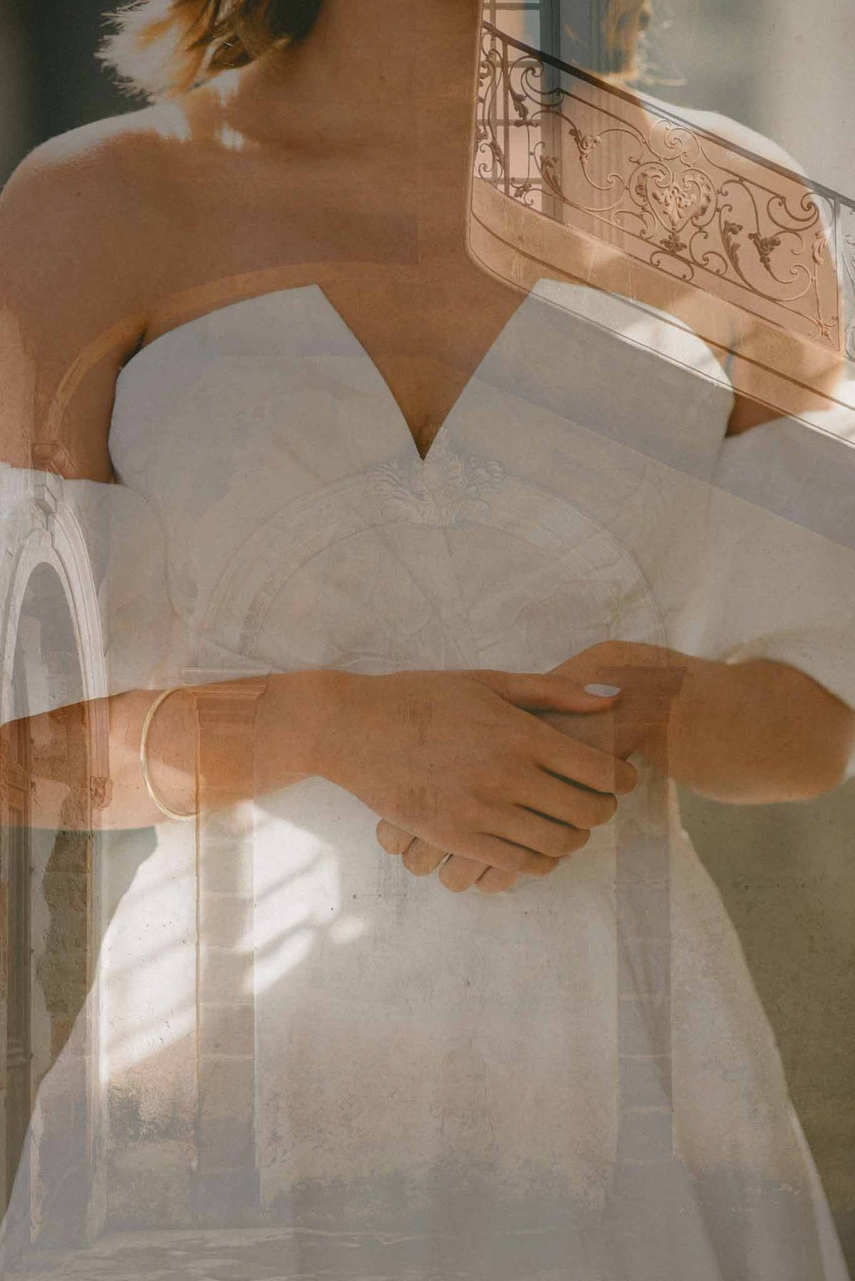 Double-exposure portrait of bride in strapless gown overlaid with chateau ironwork and stone arches