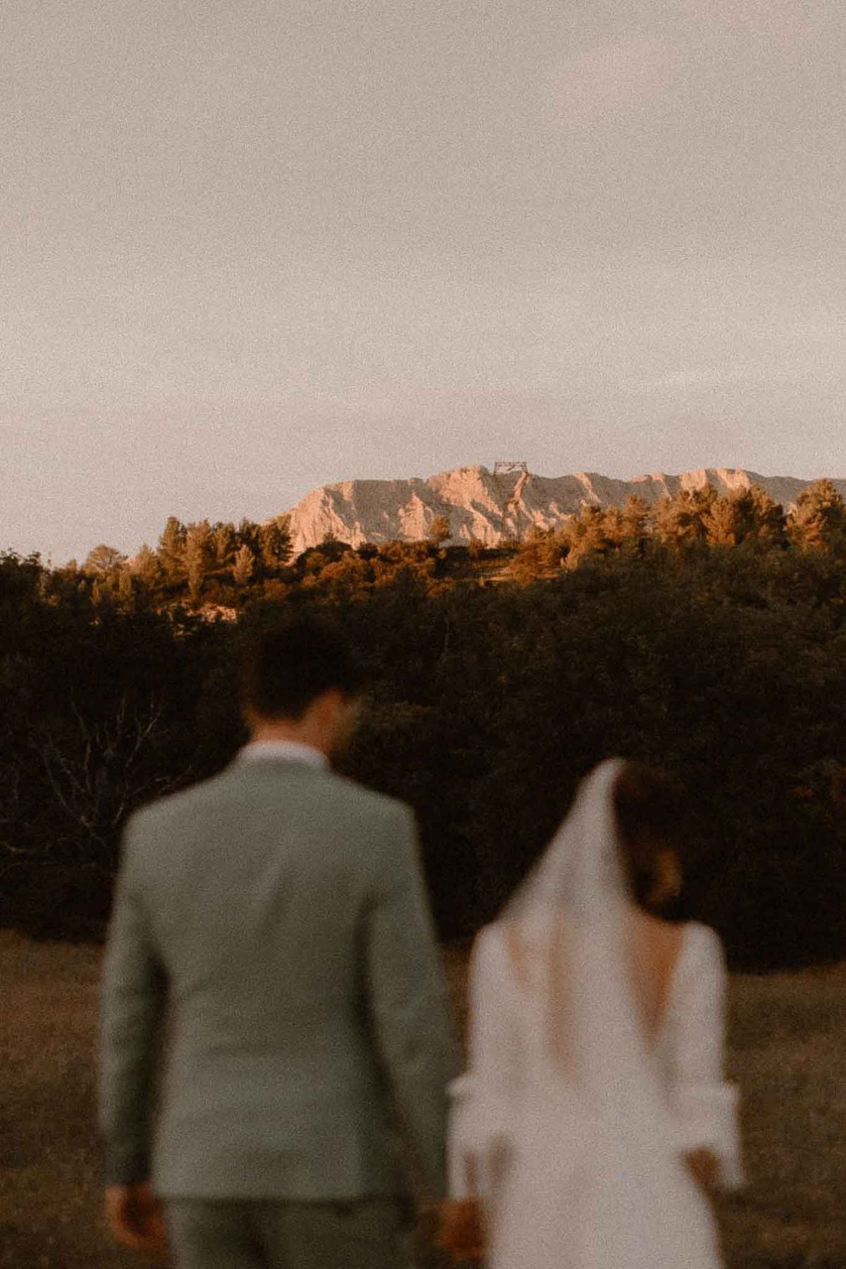 Out-of-focus couple with cathedral veil before sharp Sainte-Victoire mountain at golden hour