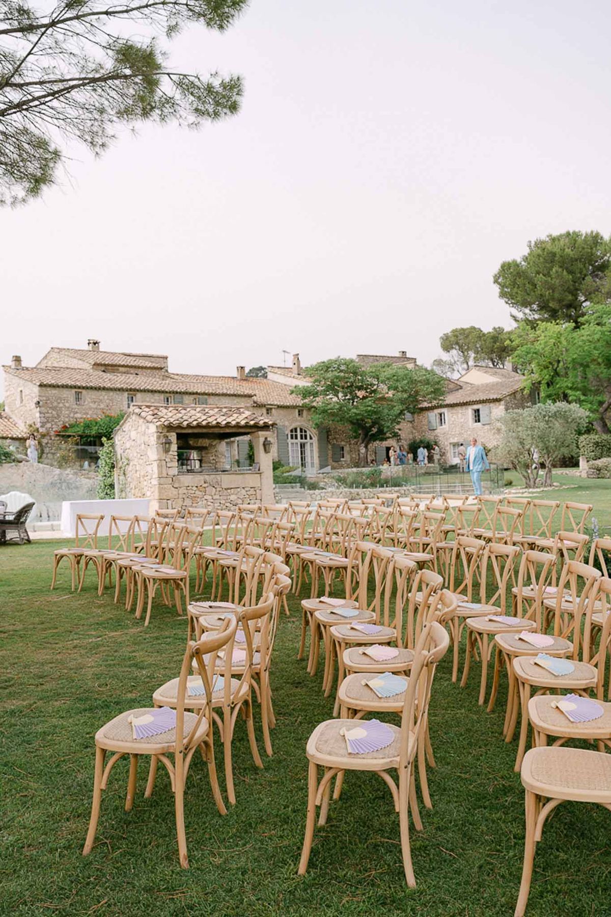 Tuscan stone villa with ceremony chairs on lawn, terracotta roofs, and climbing greenery