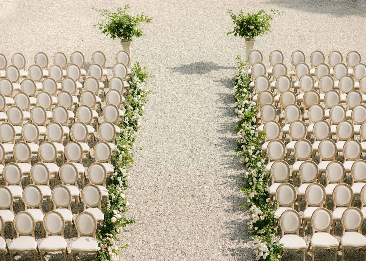 Overhead view of outdoor ceremony seating with wood chairs, ivy aisle borders, and white floral planters