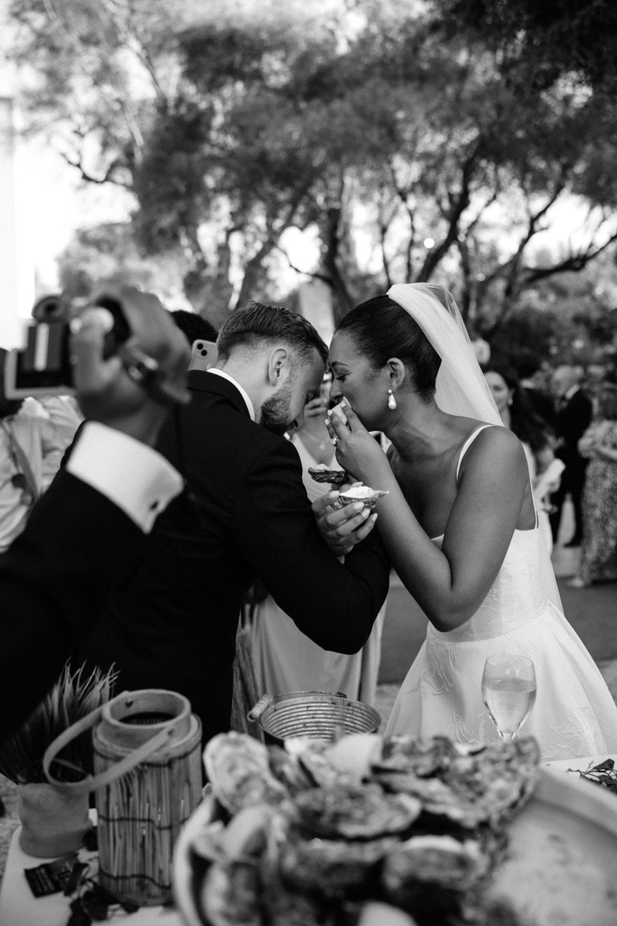 Bride and groom sharing food during outdoor wedding reception in garden setting