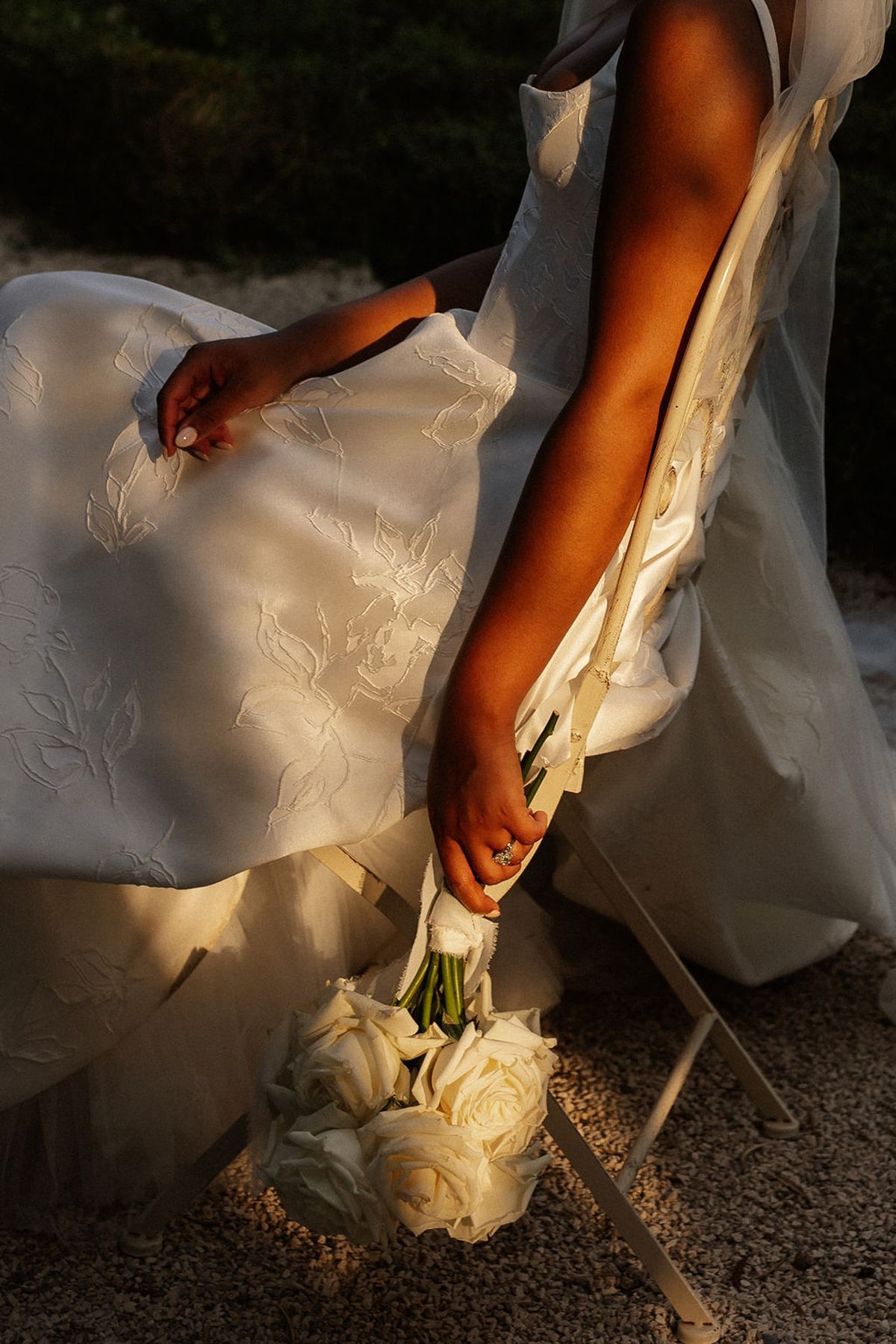 Bride holding cream rose bouquet with diamond ring during outdoor golden hour portrait session