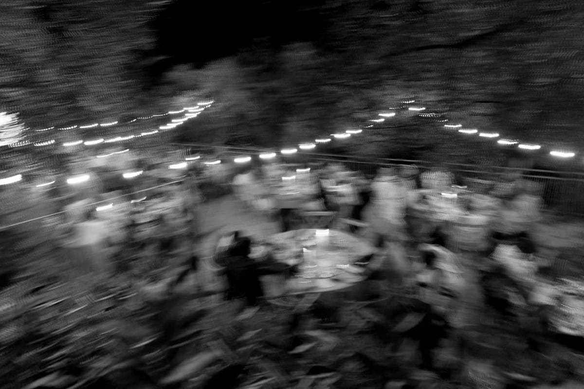 Reception celebration with motion blur showing guests at tables under string lights in indoor venue