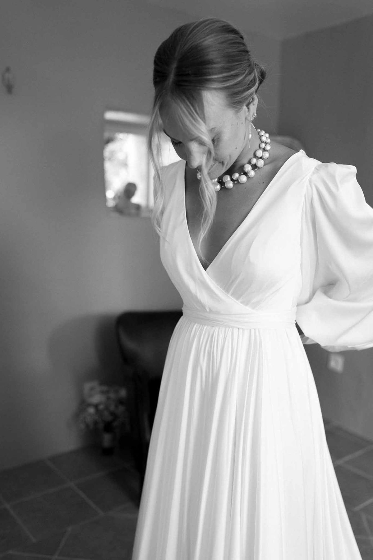 Black and white bridal portrait in ivory gown with pearl necklace in indoor preparation space
