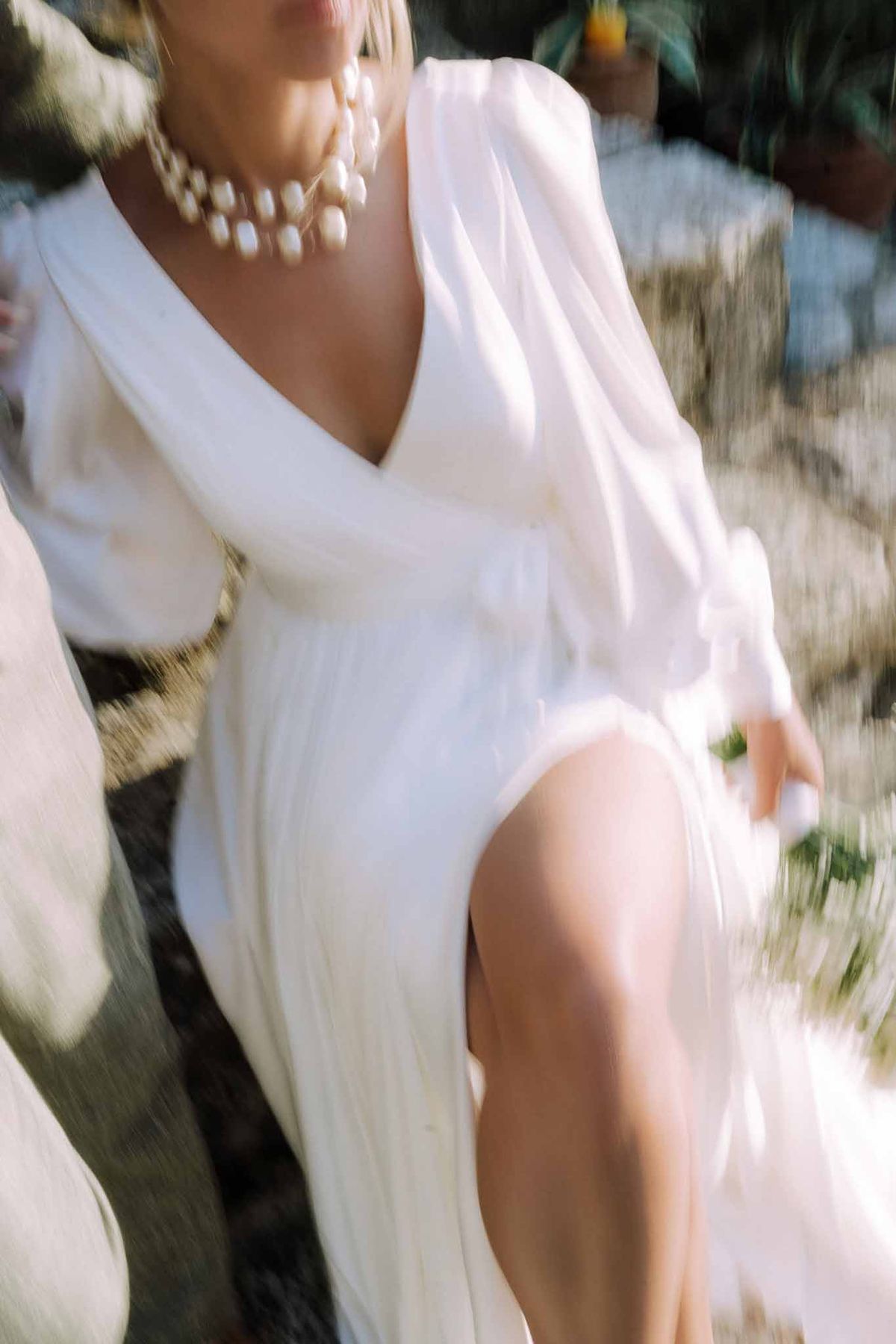 Bride in ivory crepe wedding dress with pearl necklace in outdoor garden setting