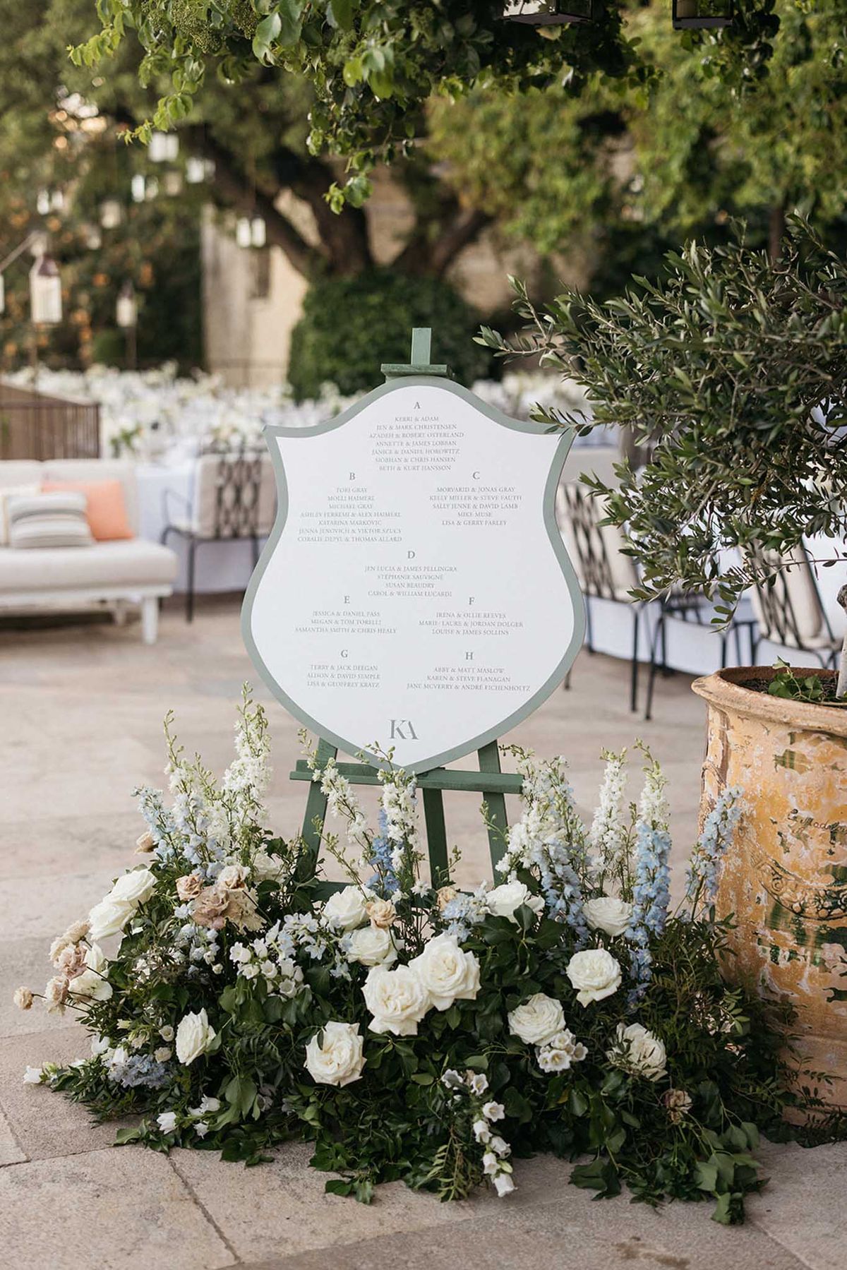 Wedding seating chart display with floral arrangement in garden courtyard reception setting
