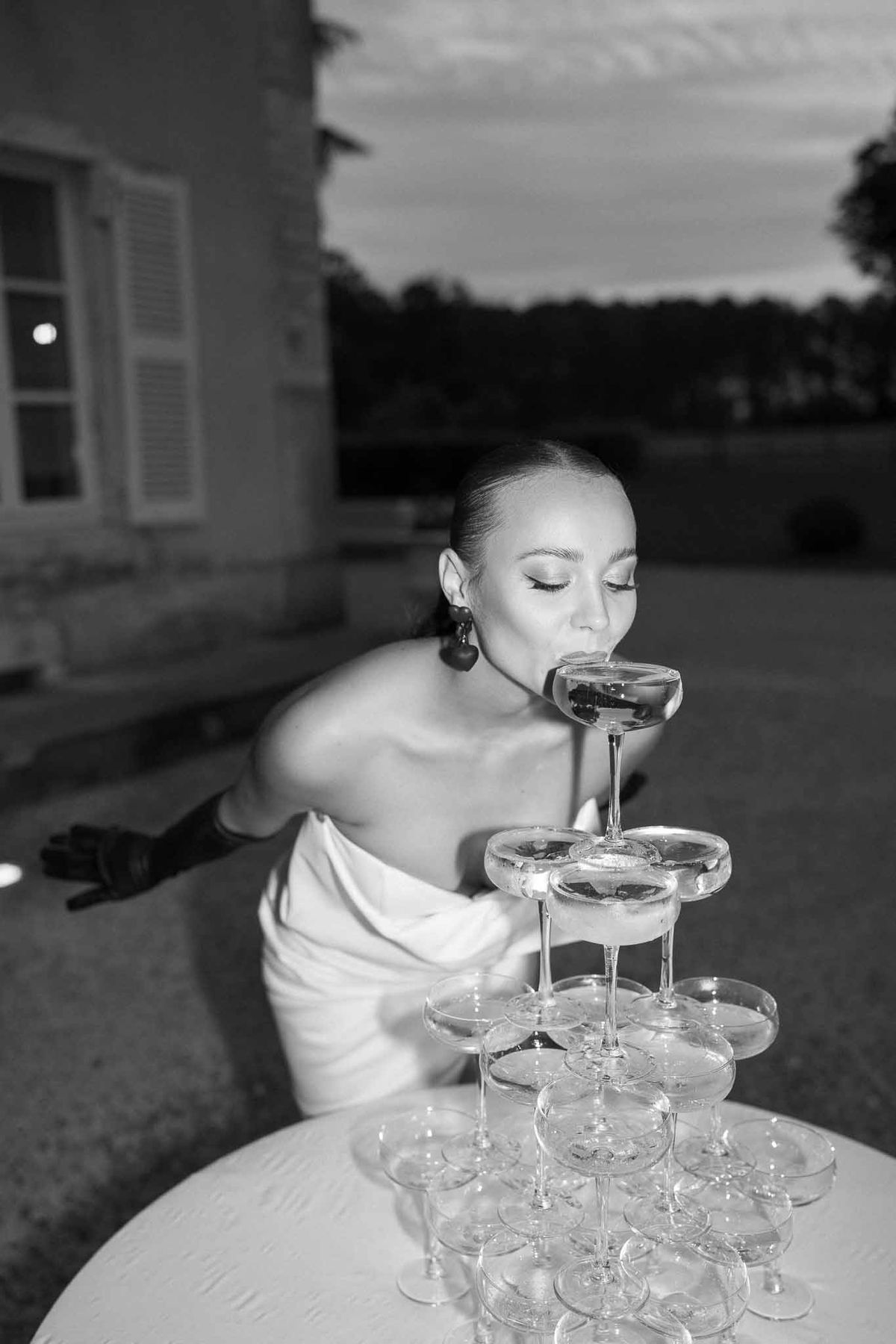 Bride drinking from champagne tower at outdoor wedding reception