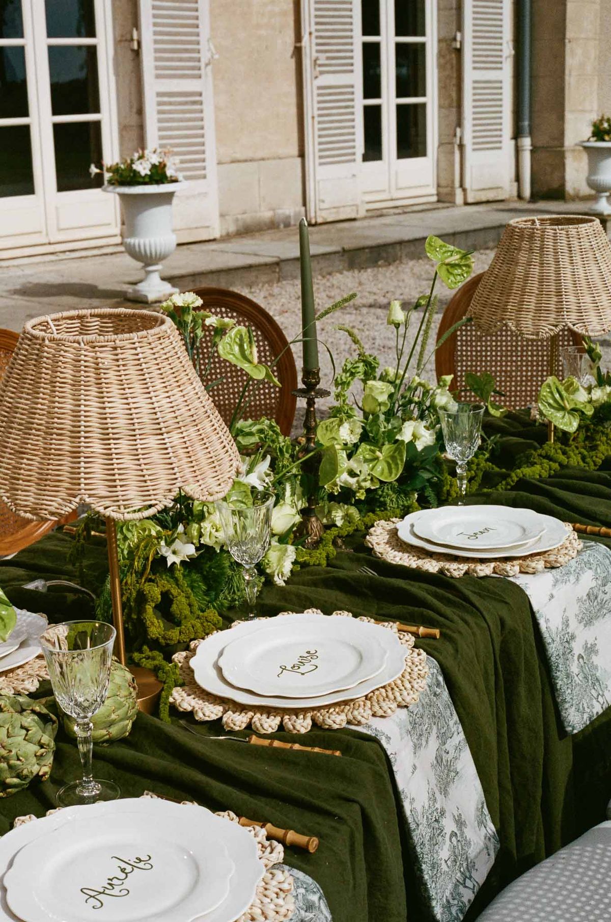 Reception table setting with green linens and white florals in classical stone courtyard