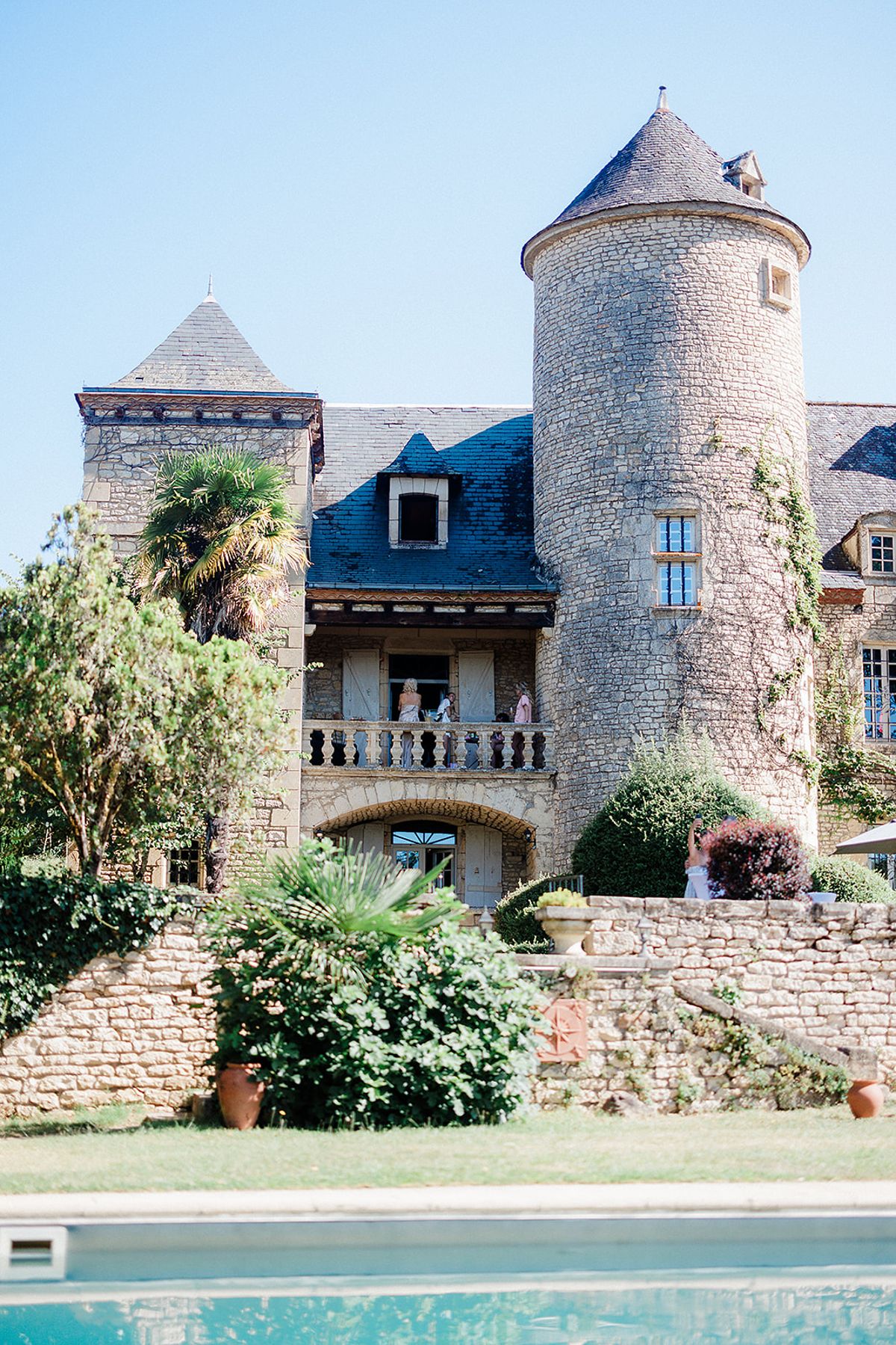 Castle wedding venue with stone towers and swimming pool in foreground