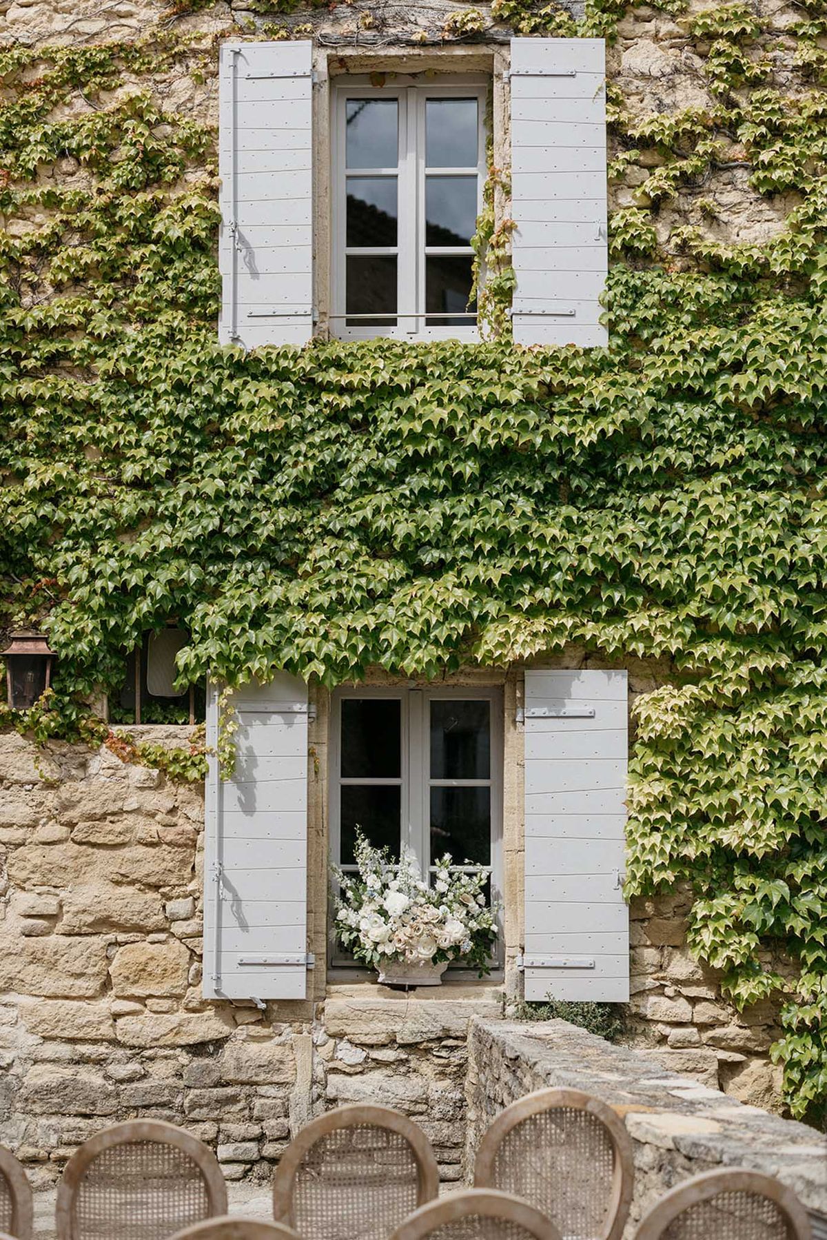 Historic stone building facade with ivy-covered walls and shuttered windows at rustic European venue