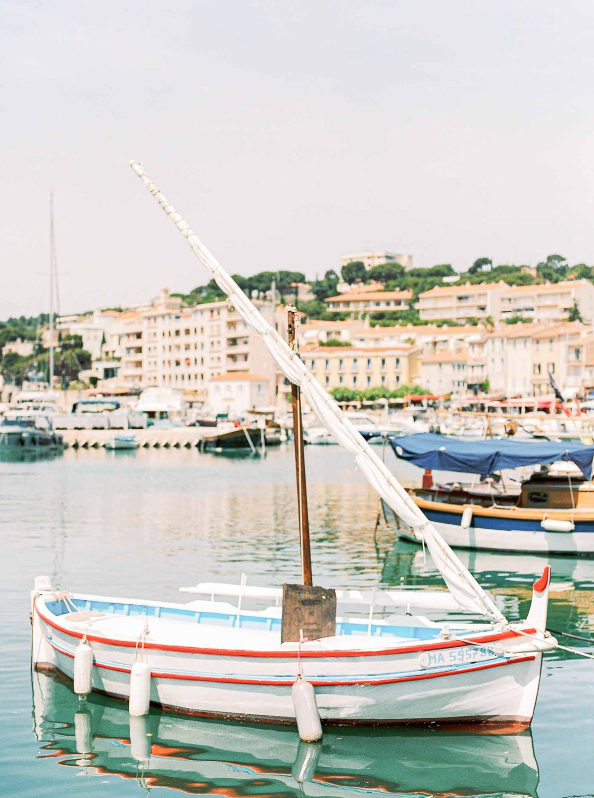 Traditional fishing boat moored in Mediterranean harbor with hillside village backdrop for coastal wedding venue