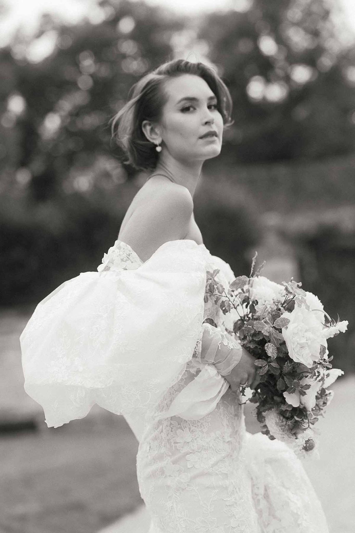 Black and white bridal portrait of bride in lace wedding dress in garden setting
