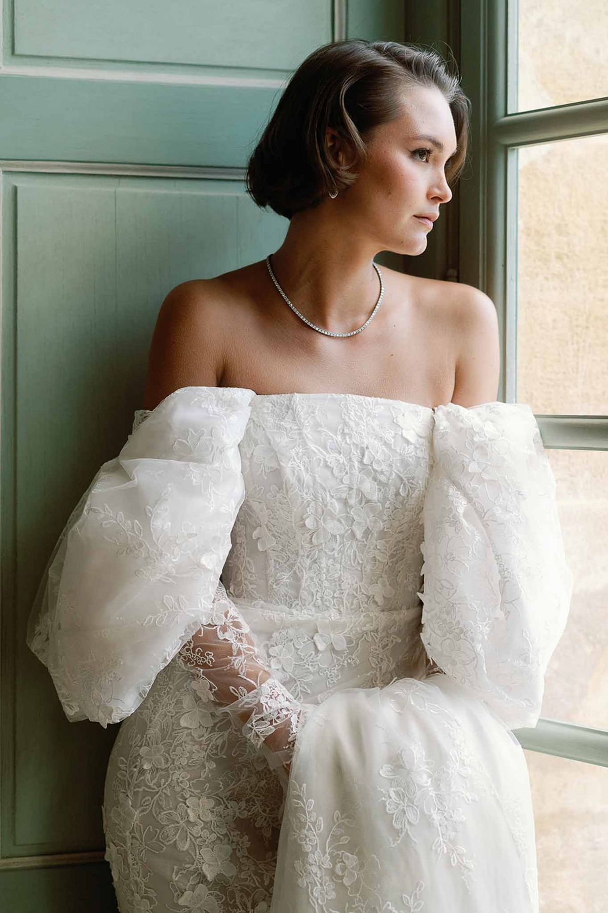 Bride in ivory lace wedding dress with diamond necklace in sage green paneled room