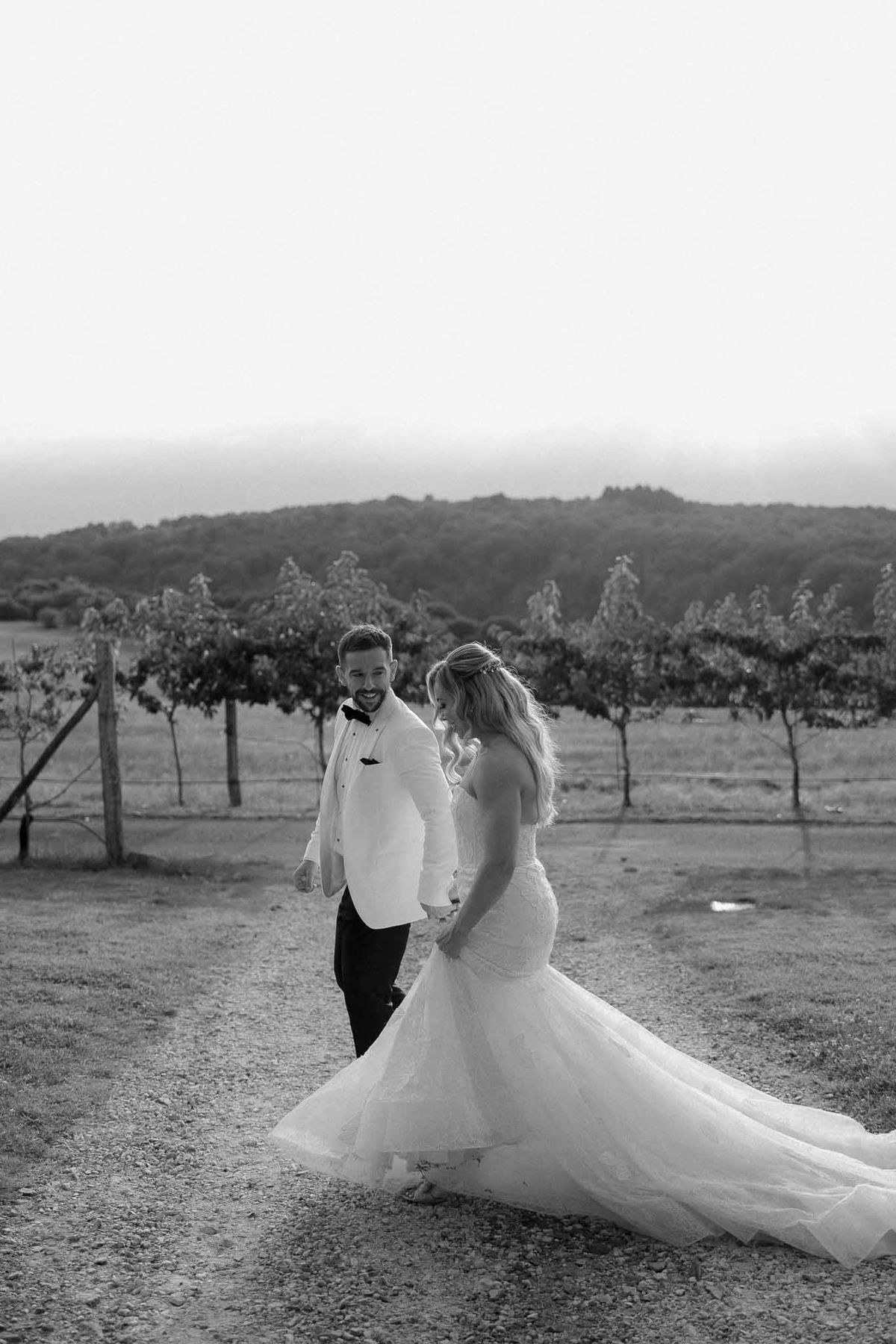 Bride and groom portrait on gravel road in vineyard with rolling hills background