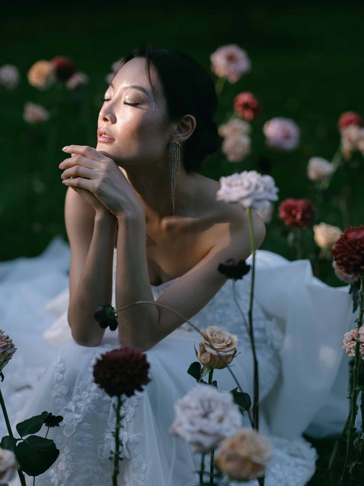 Bride in ivory lace dress with burgundy and pink flowers in garden setting