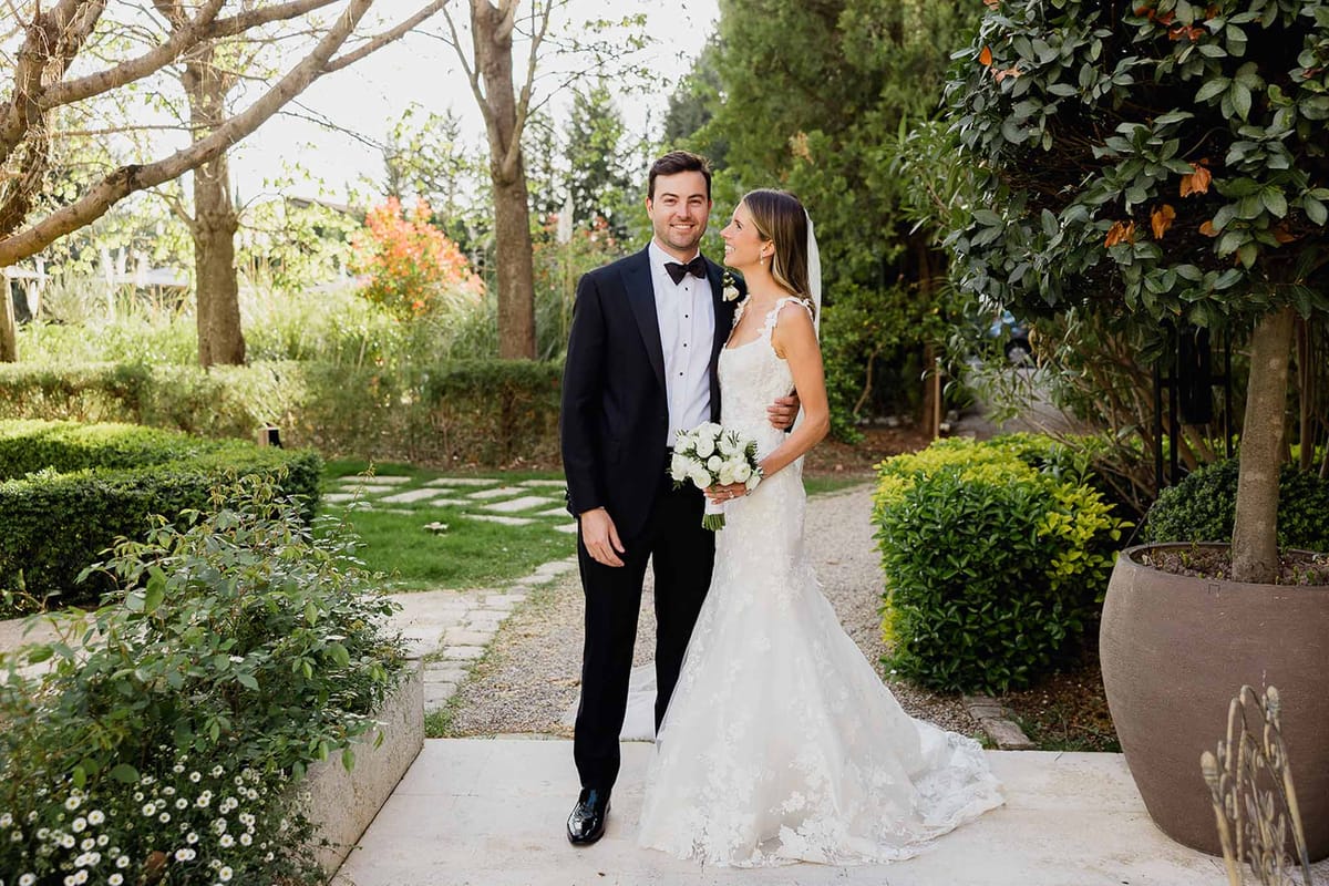 Bride and groom posing together on stone pathway in formal garden setting