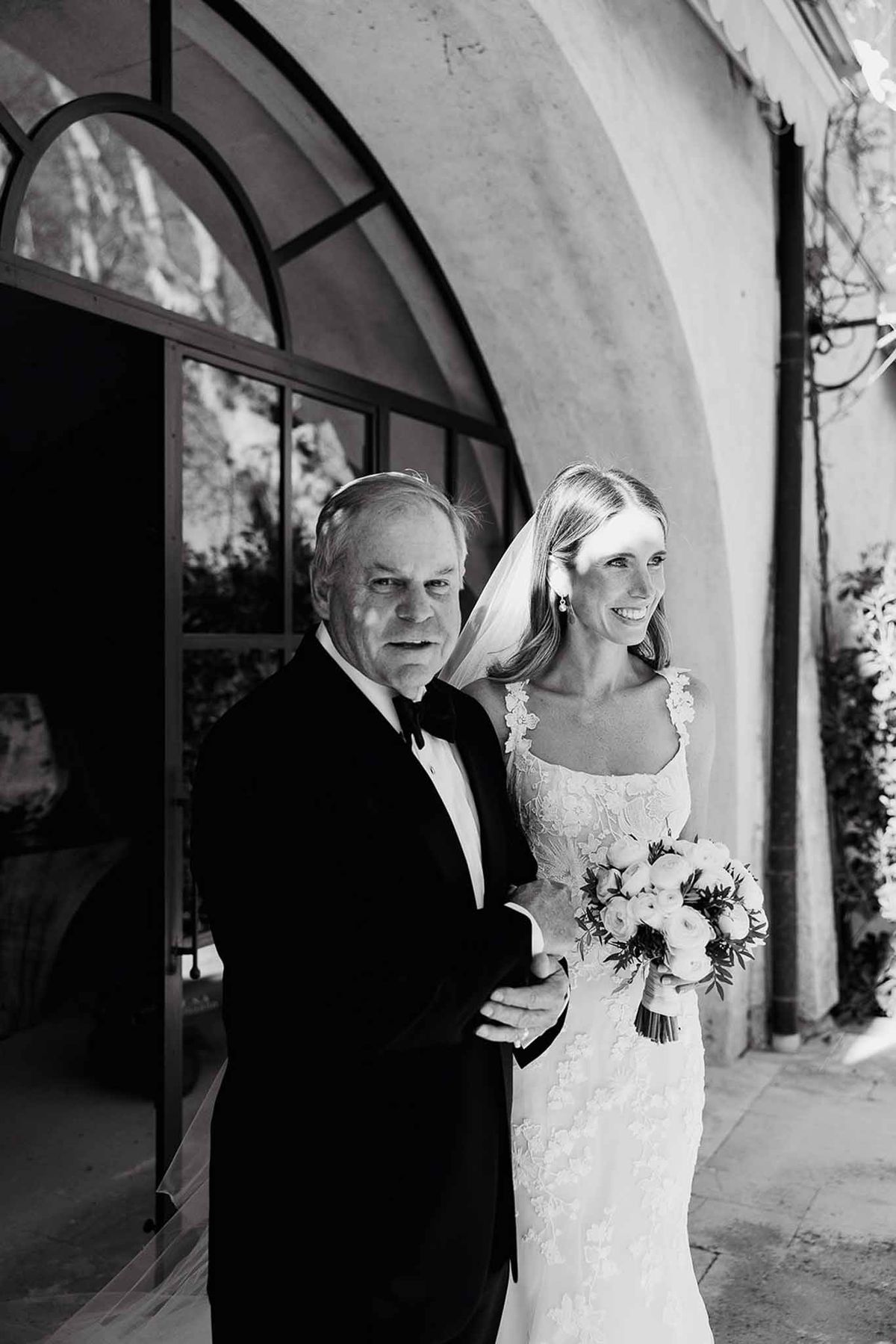 Bride and groom posing together outside modern venue with curved architecture