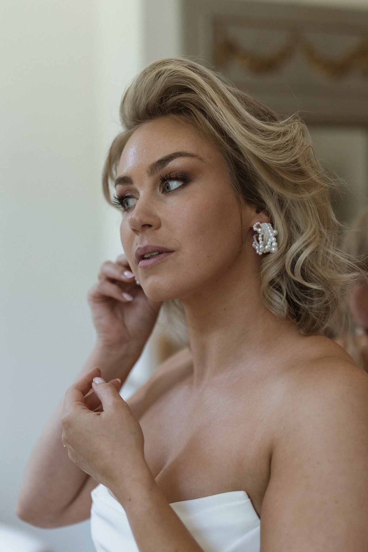 Bride in strapless white dress with crystal earrings during wedding preparation portrait