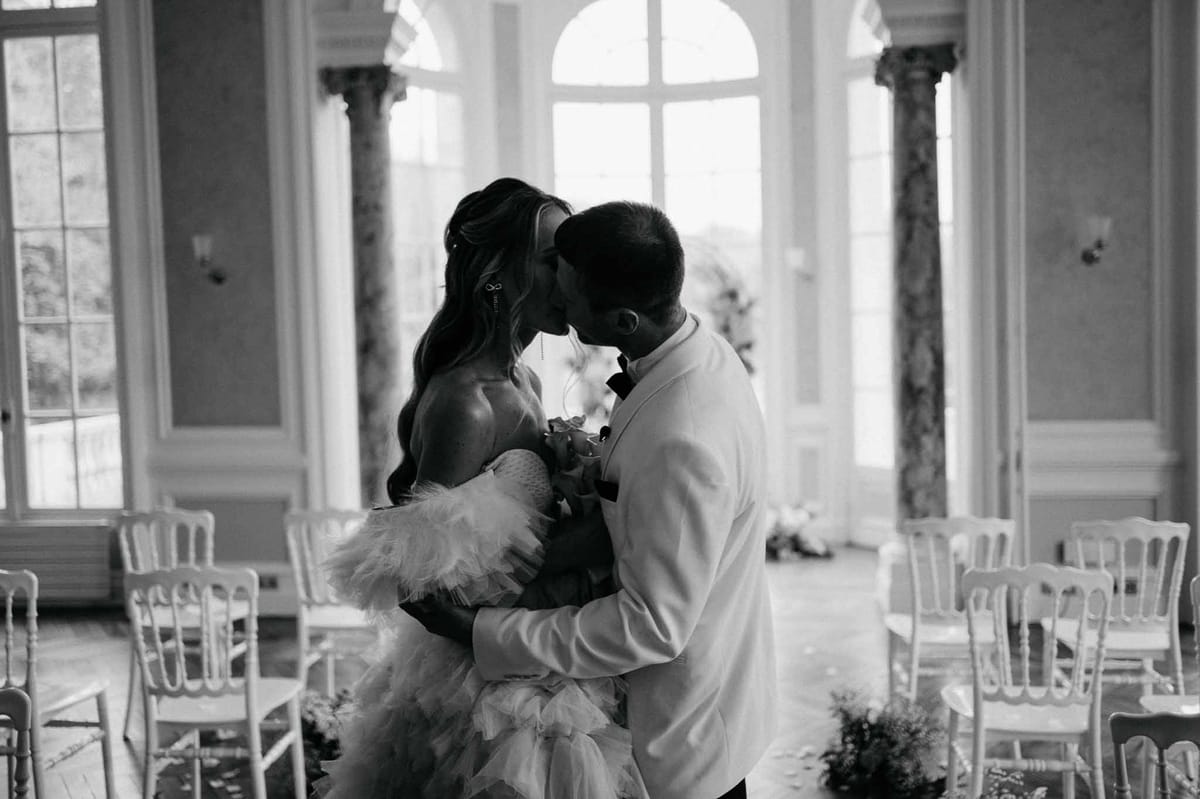 Couple sharing intimate dance moment in classical ceremony space with arched windows