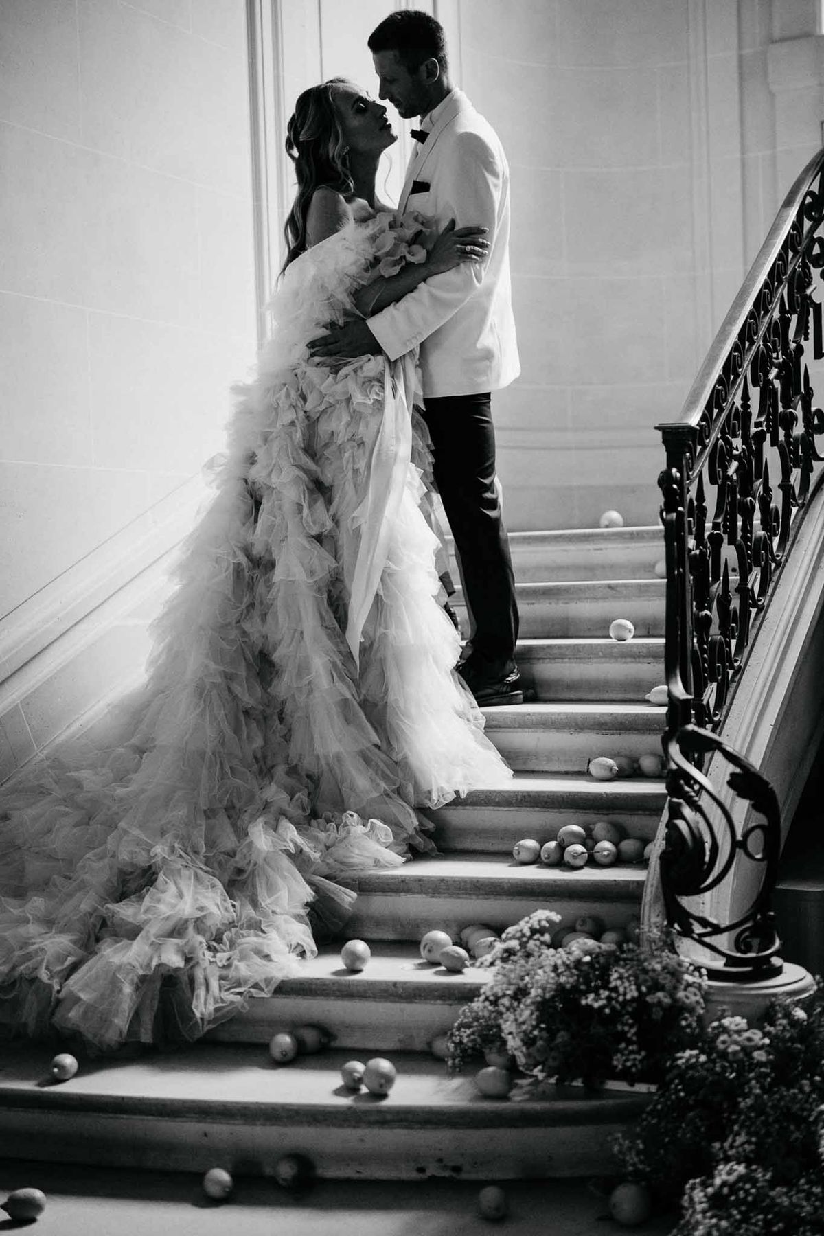 Bride and groom portrait on grand staircase with wrought-iron railings at elegant indoor venue