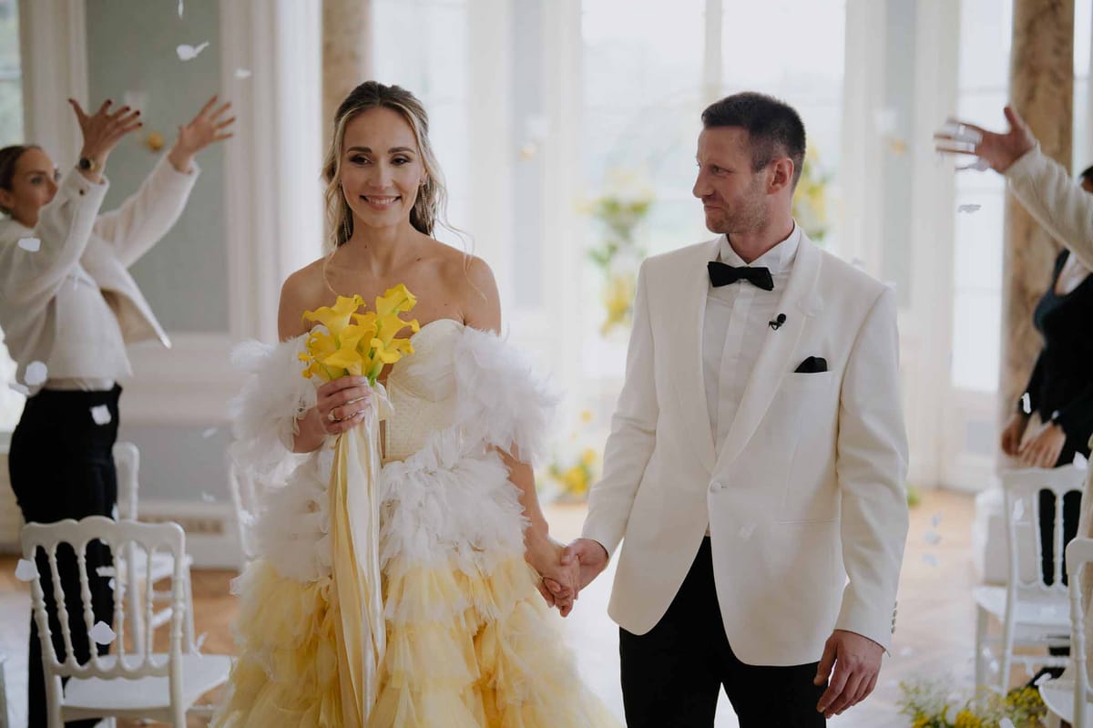 Bride and groom walking down aisle during recessional at modern indoor wedding venue with floor-to-ceiling windows