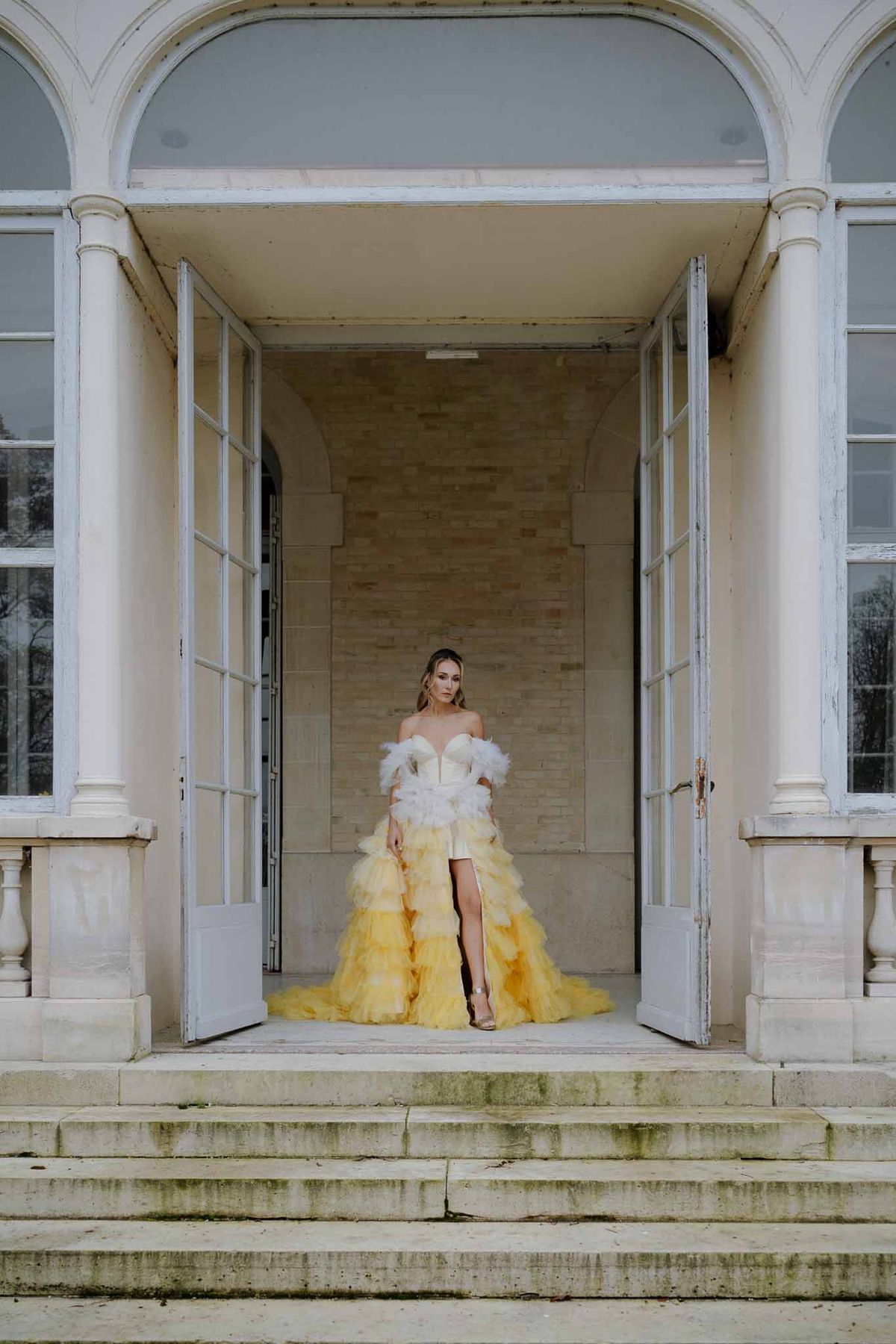 Bride in ombré yellow gown on neoclassical building steps with white columns