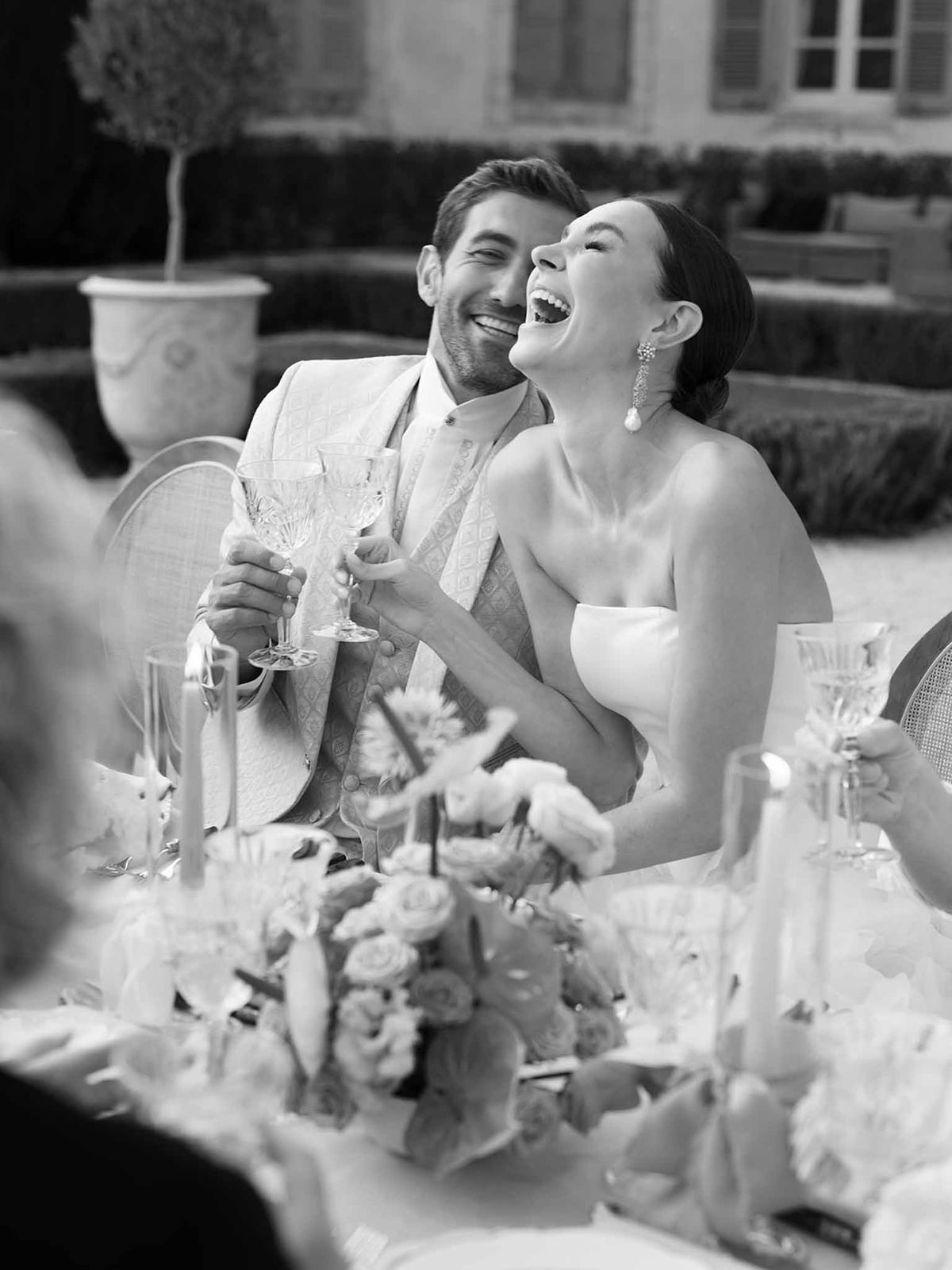 Bride and groom toasting with champagne at reception dinner table in formal courtyard venue