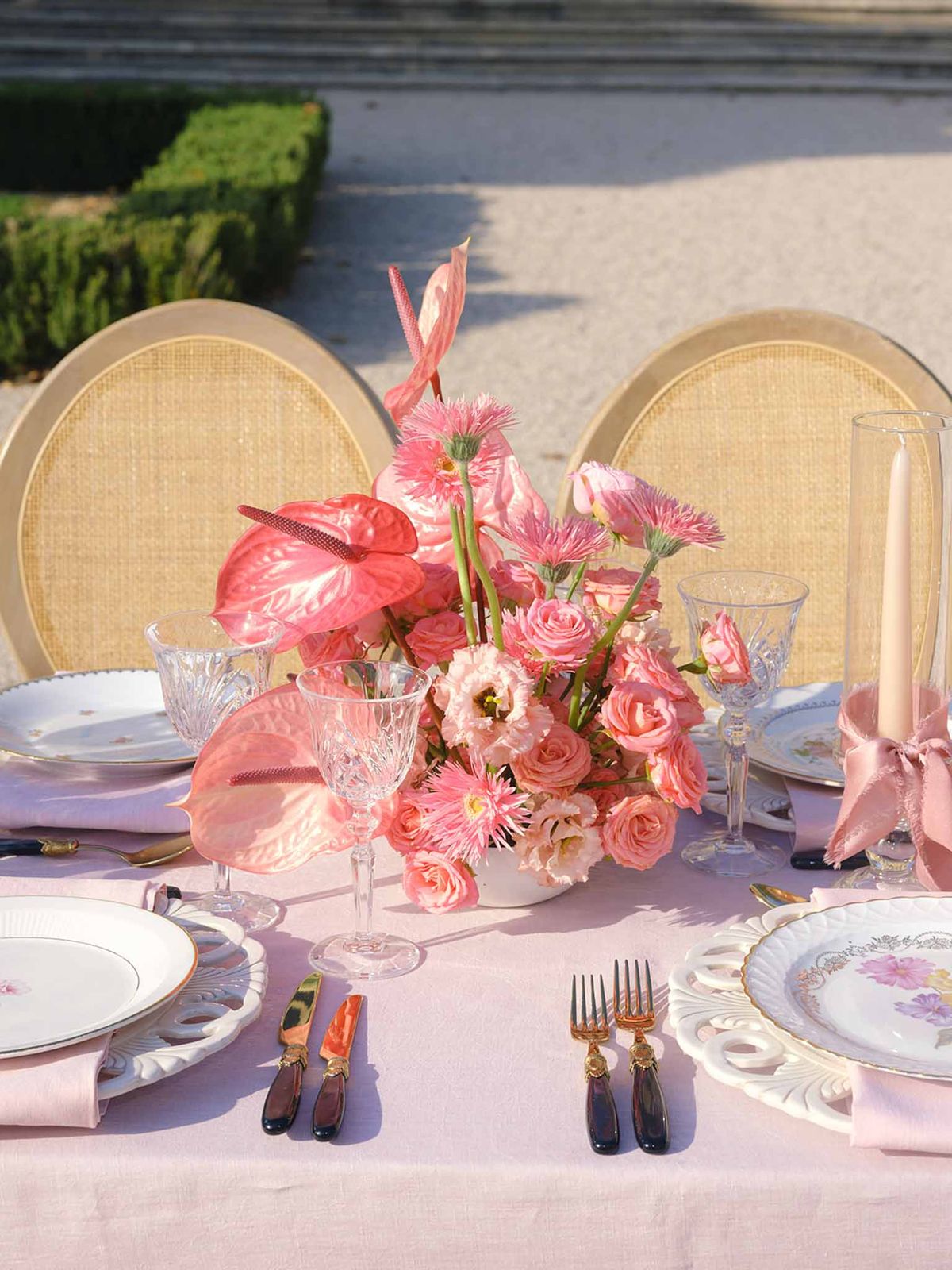 Elegant reception table setting with pink linens and coral floral centerpiece on outdoor terrace