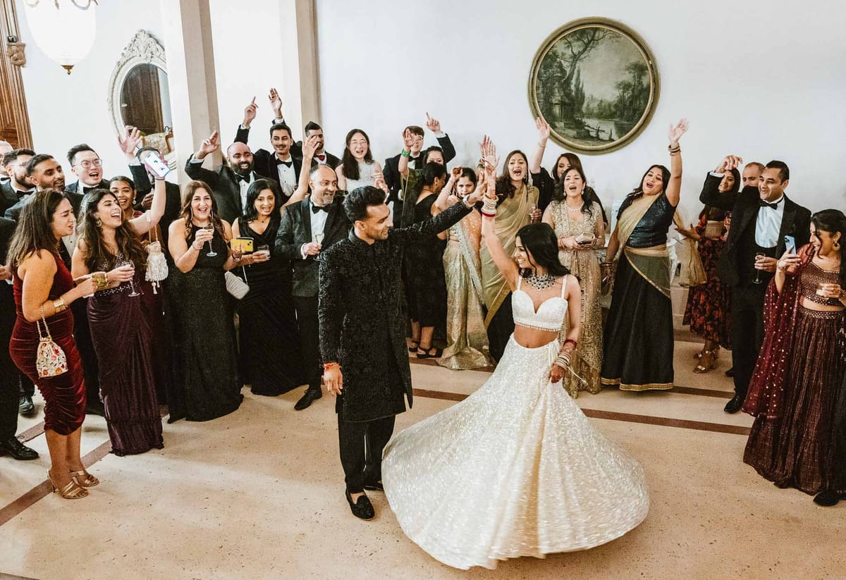 First dance with guests celebrating at elegant indoor wedding reception venue
