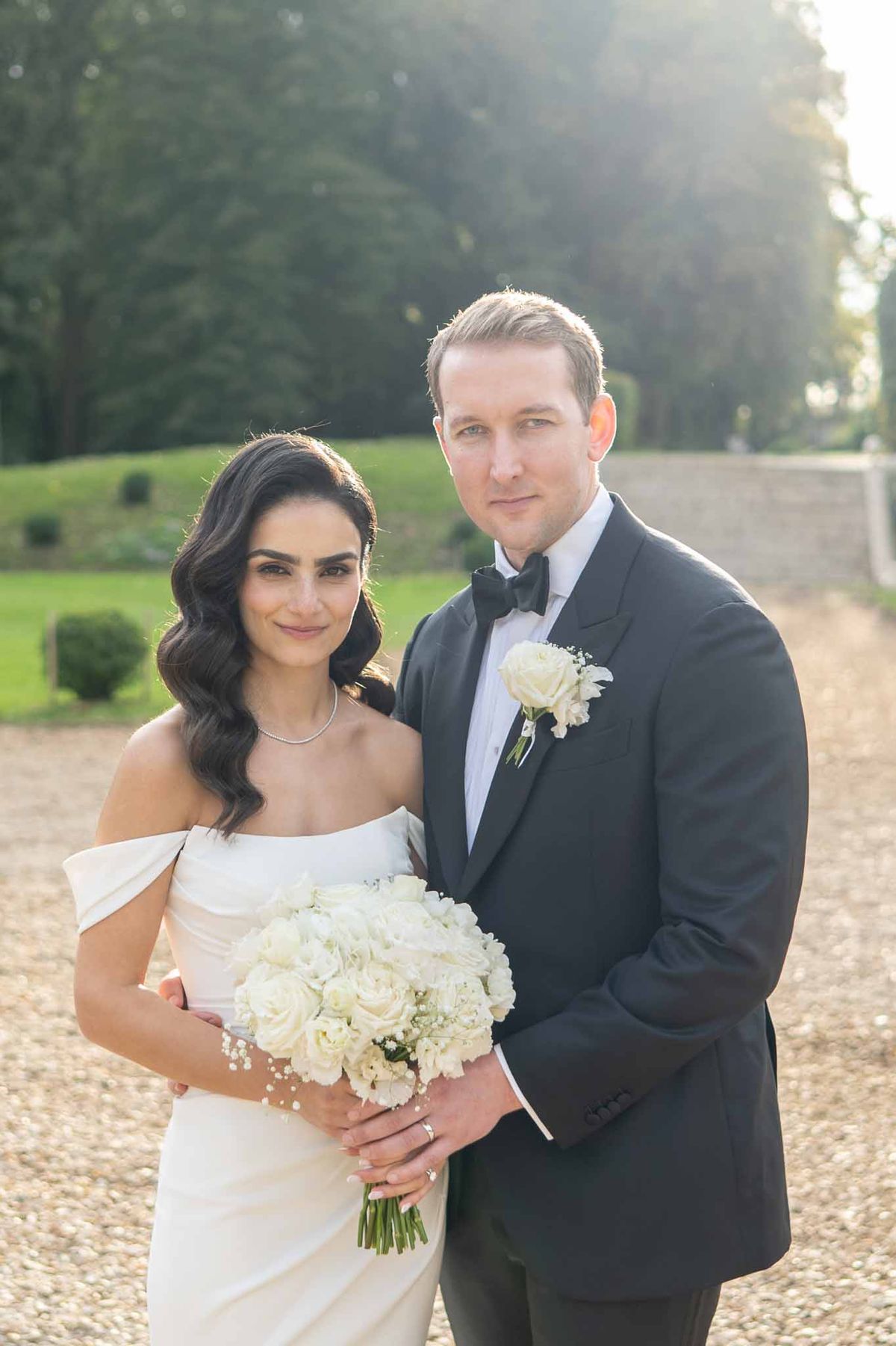Bride and groom formal portrait in estate courtyard with manicured gardens