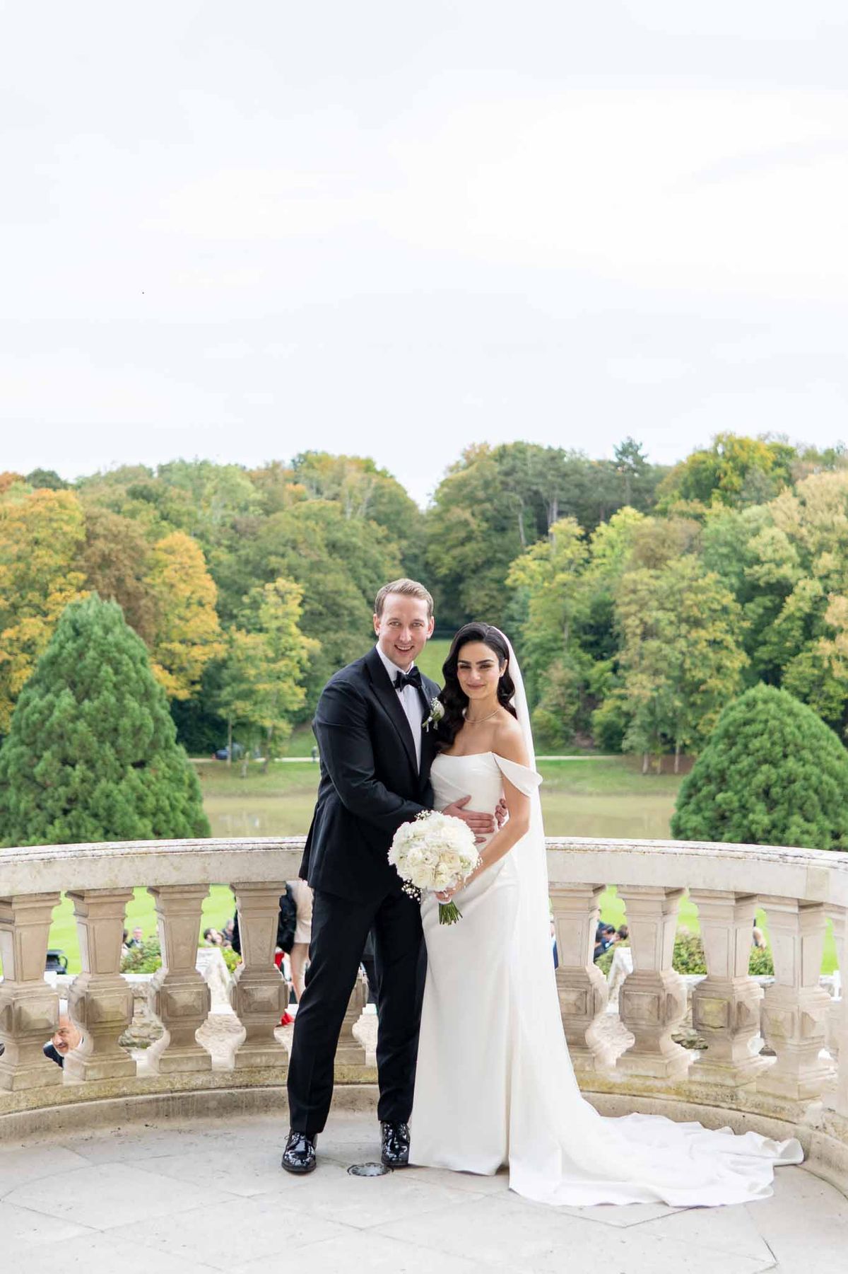 Bride and groom formal portrait on stone balcony overlooking manicured grounds