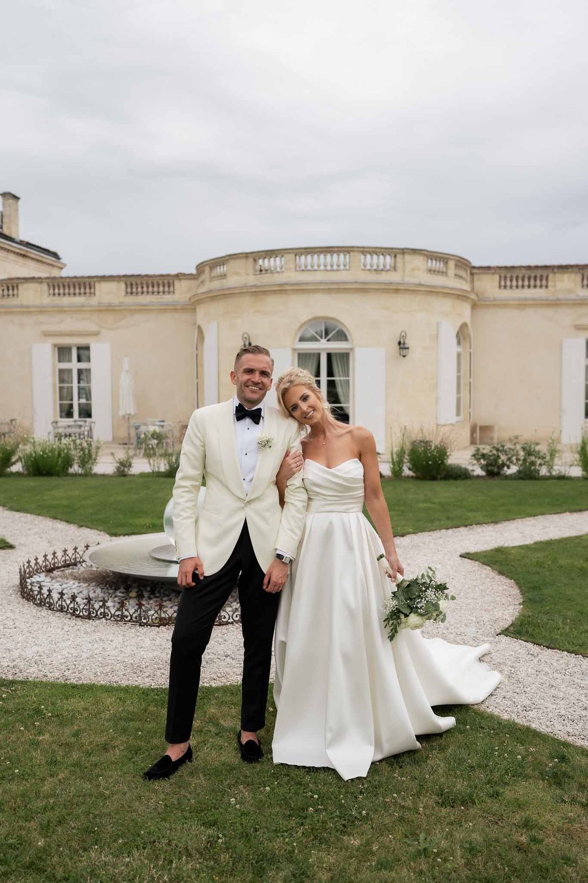 Bride and groom formal portrait in front of classical stone mansion with columns
