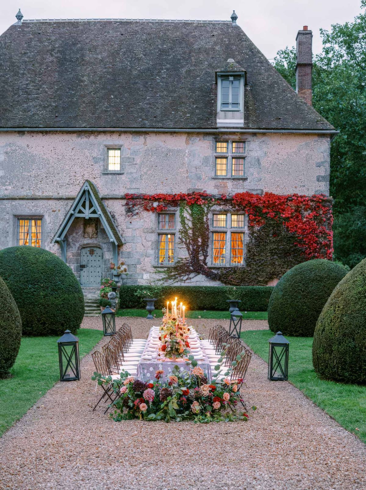 Autumn floral runner of coral dahlias and burgundy blooms with taper candles on lavender linen at manor