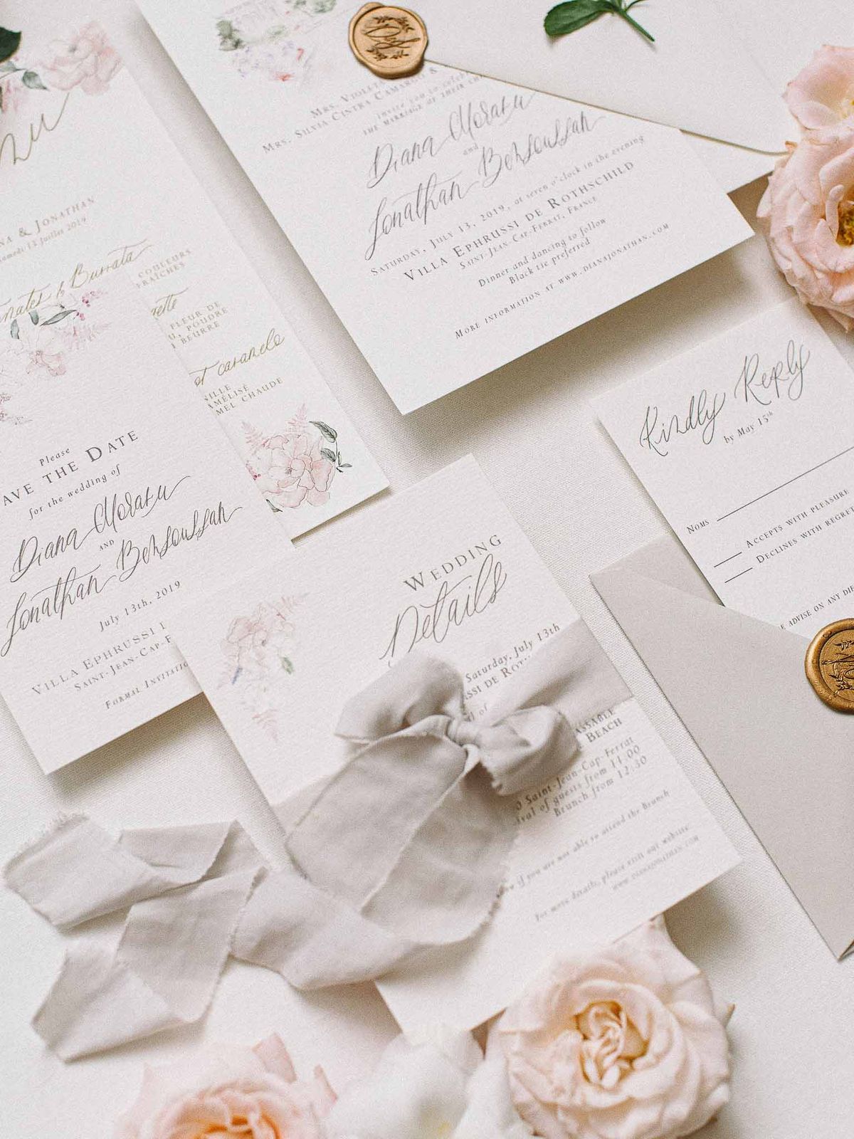 Wedding invitation suite with pink florals and gold wax seals arranged on white surface for Villa Ephrussi wedding