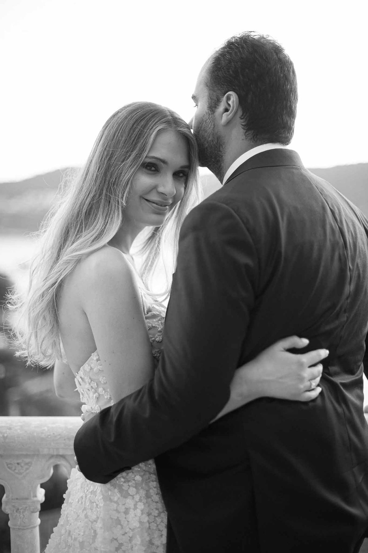 Black and white portrait of bride and groom in intimate moment outdoors with landscape background