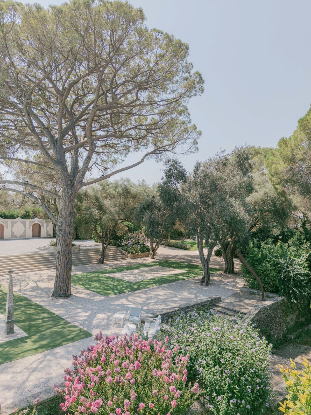 Elevated view of formal venue gardens with gravel pathways, stone terracing, and cream building facade