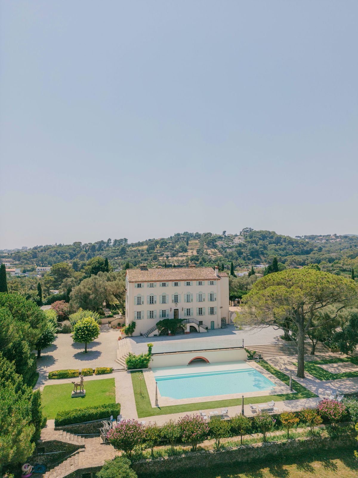 Aerial view of Provencal bastide with pool, formal gardens, cypress trees, and terracotta roof