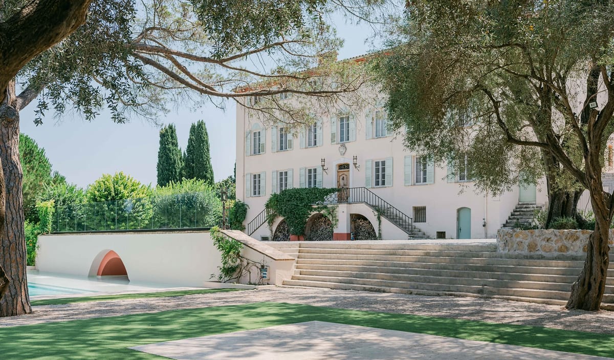 Provencal bastide manor with cream walls, blue shutters, stone arcades, pool area, and manicured lawn