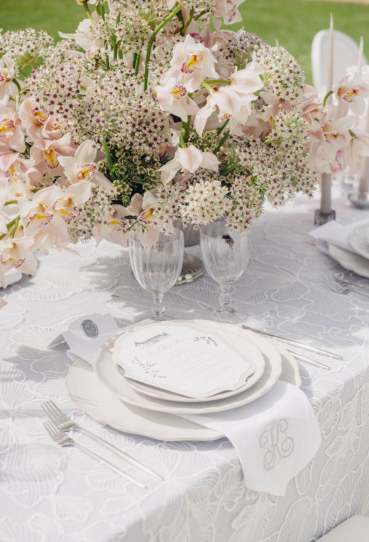 Wedding reception table setting with orchid centerpiece and ivory linens