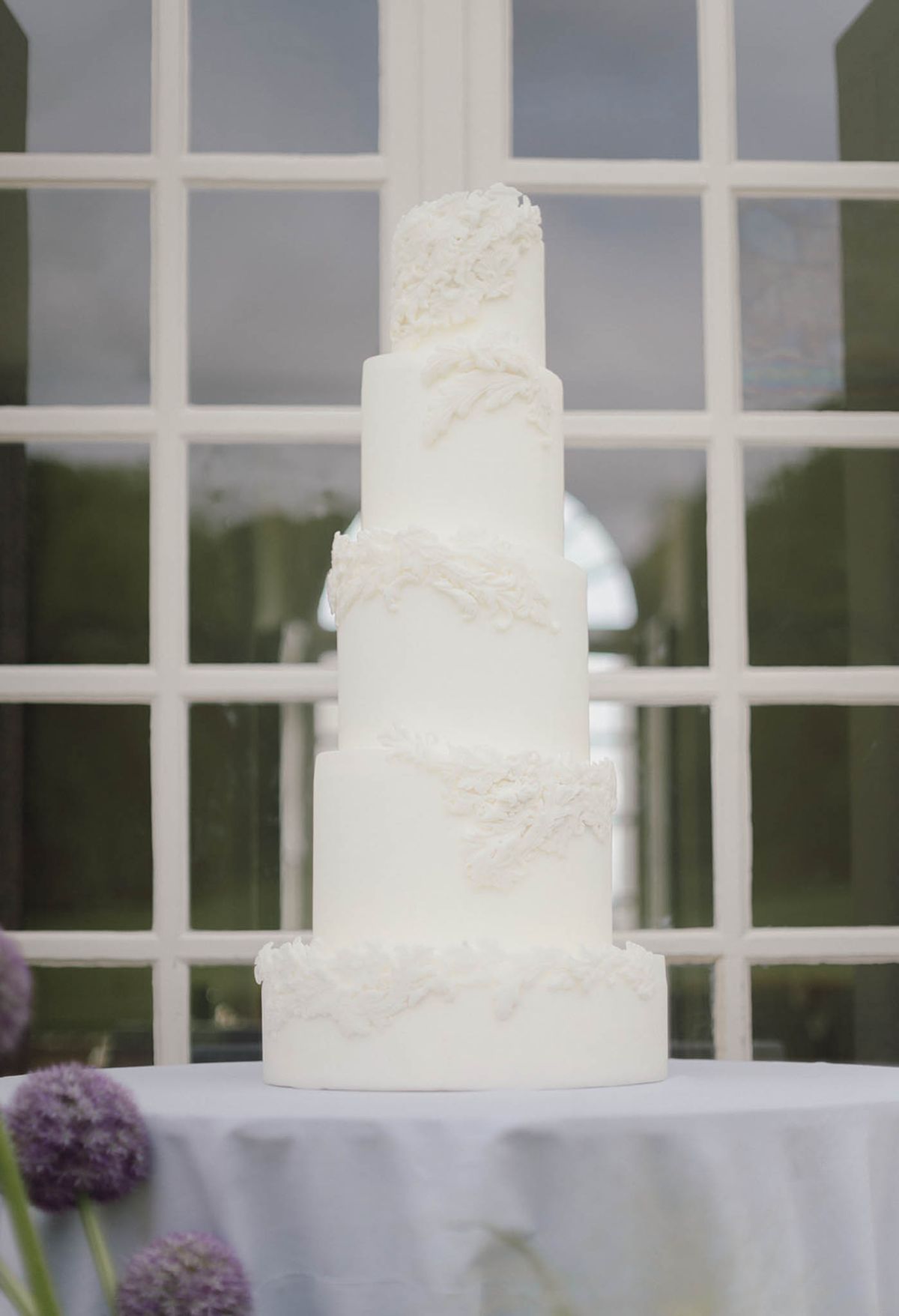 Five-tier white wedding cake with textured frosting at elegant reception venue