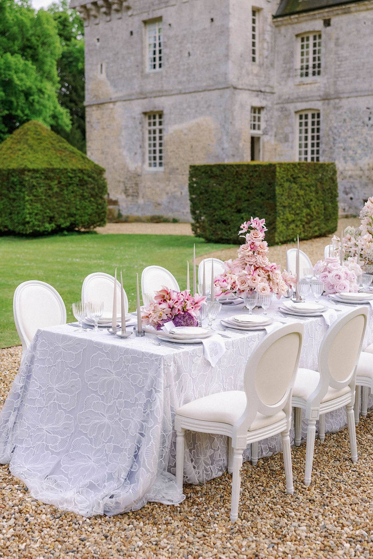 Elegant reception table with floral centerpieces in château courtyard with historic stone building