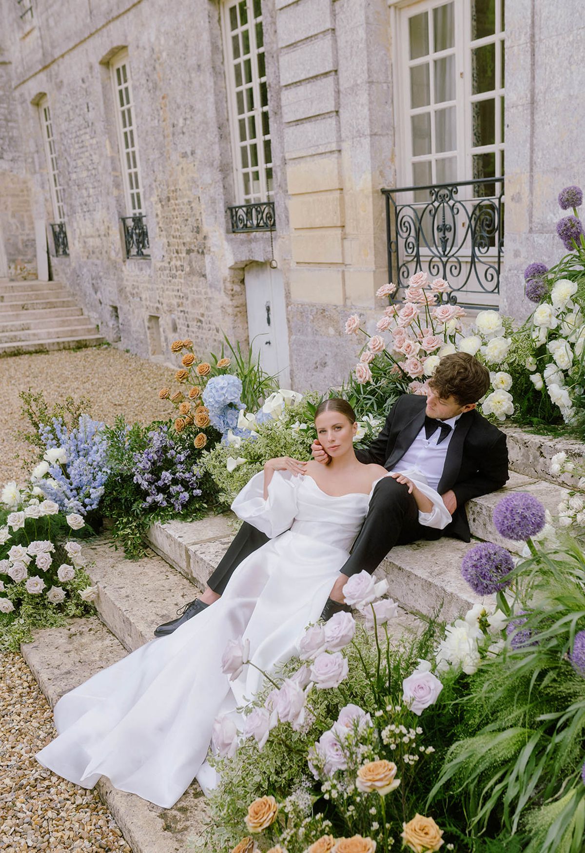Bride and groom portrait in stone courtyard with floral installations at French manor